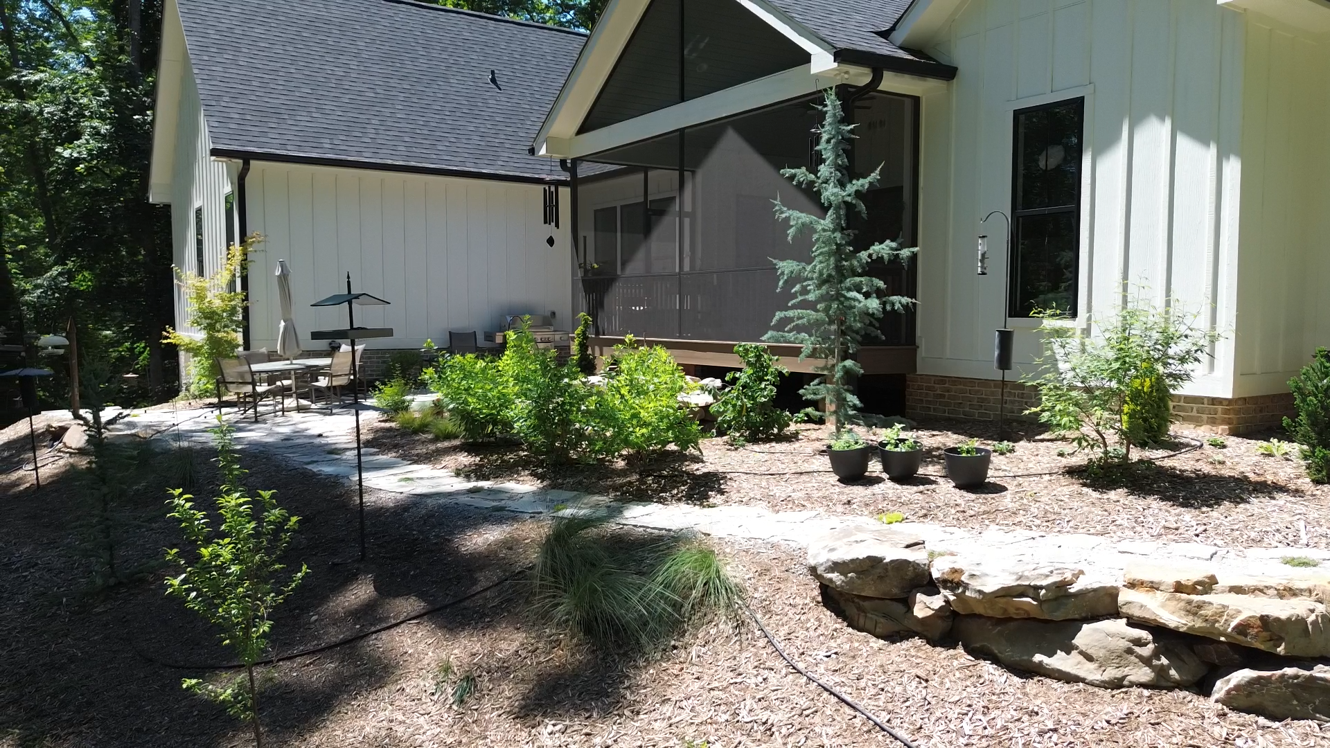 Layered planting, natural stone, and subtle grade transitions help the landscape feel rooted within its surroundings, creating a seamless connection between home and forest.