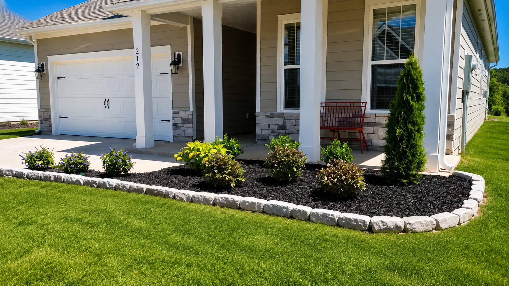 A layered front garden softens the architecture with structured evergreen form, seasonal color, and a crisp stone edge that gives the entry a finished sense of arrival.