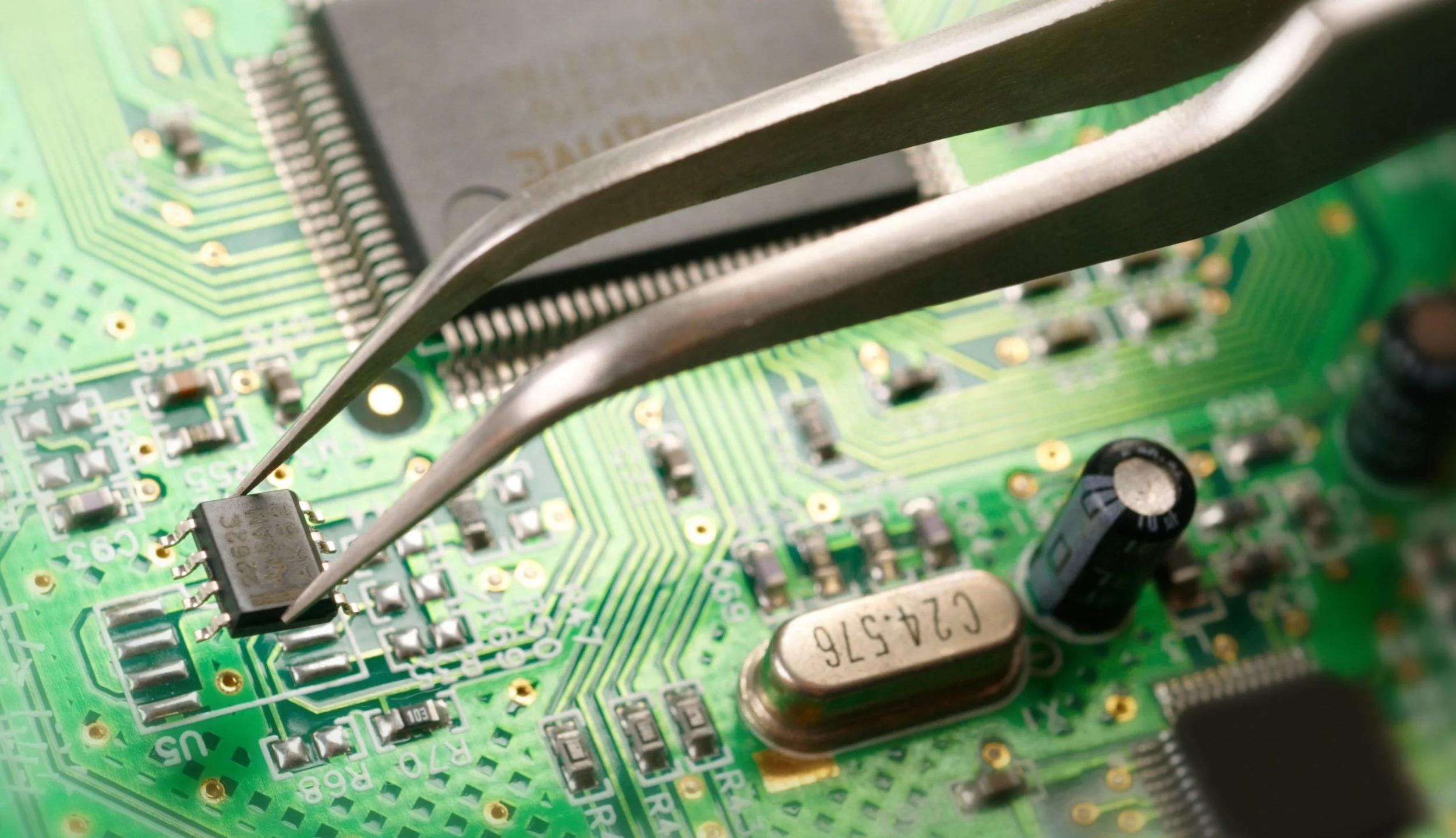 Close-up of a green printed circuit board (PCB) with electronic components and three metal heatsinks.
