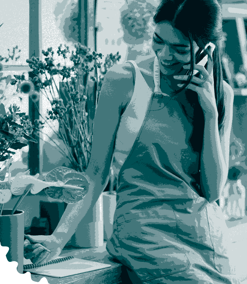 Young woman on the phone, smiling while writing in notepad