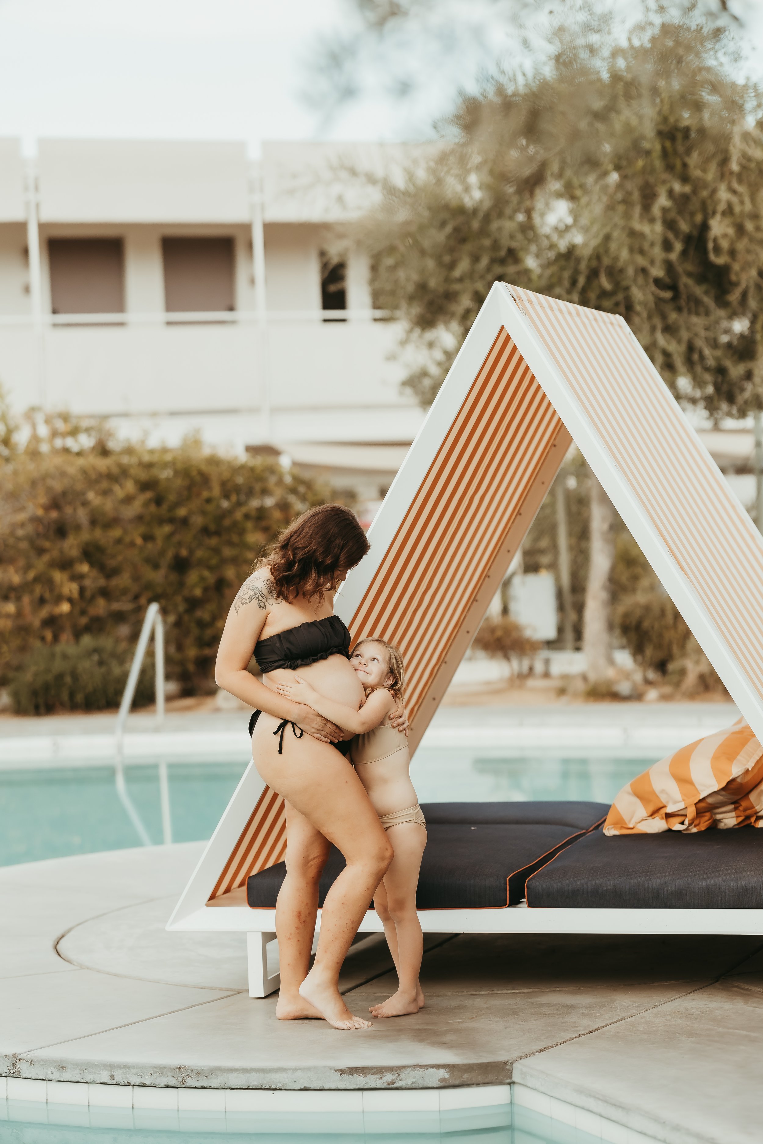 Sibling hugging mother's pregnant belly during family maternity photography session