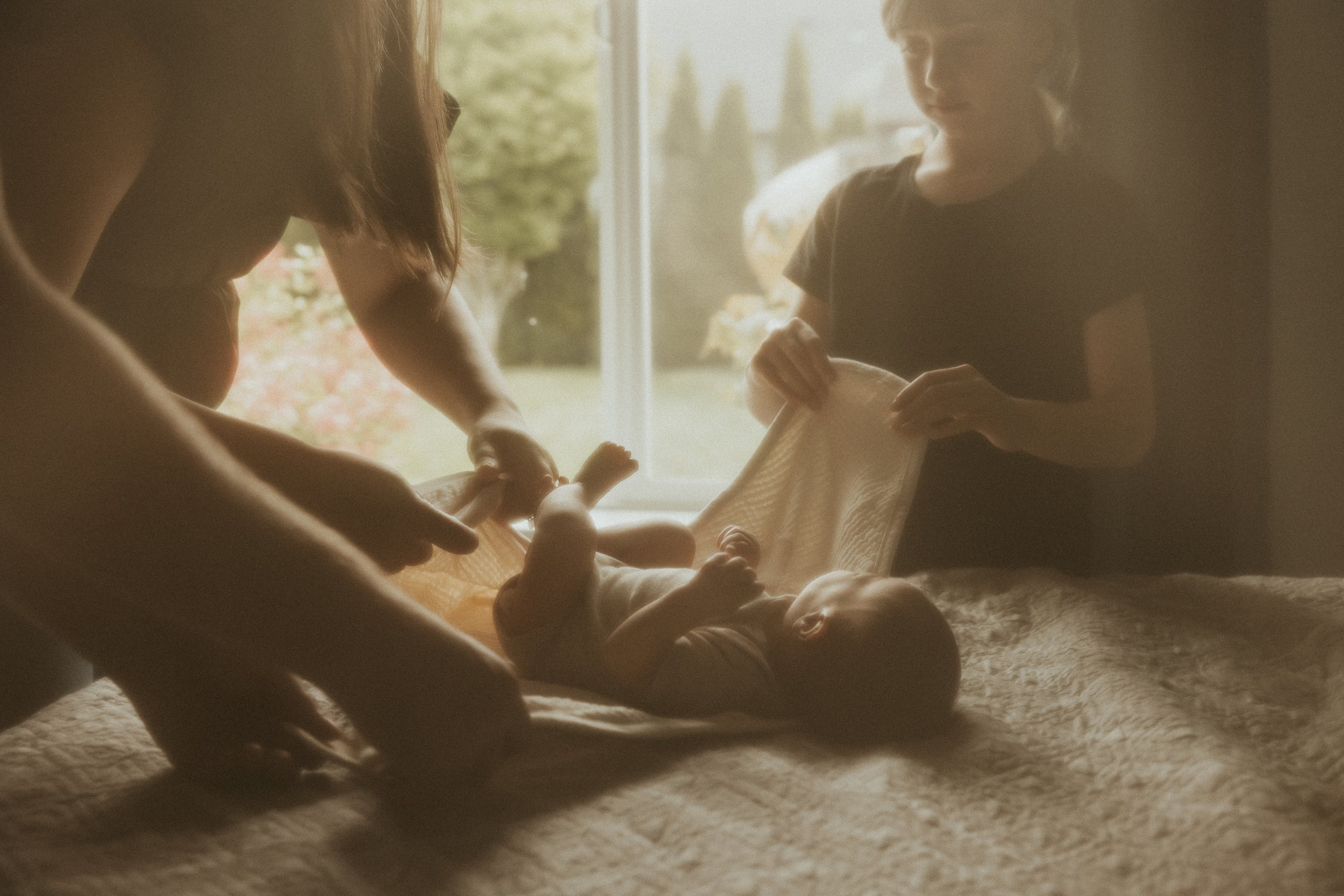 Family swaddling newborn during photography session