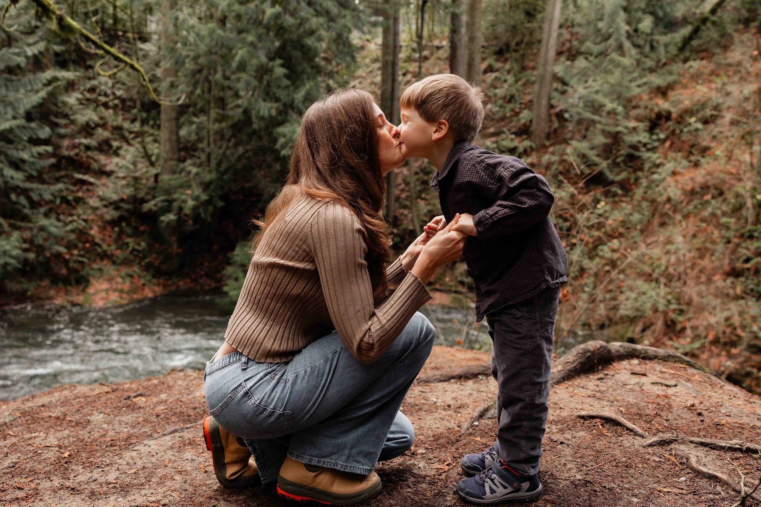 Mother kissing her son during playful family photography session 