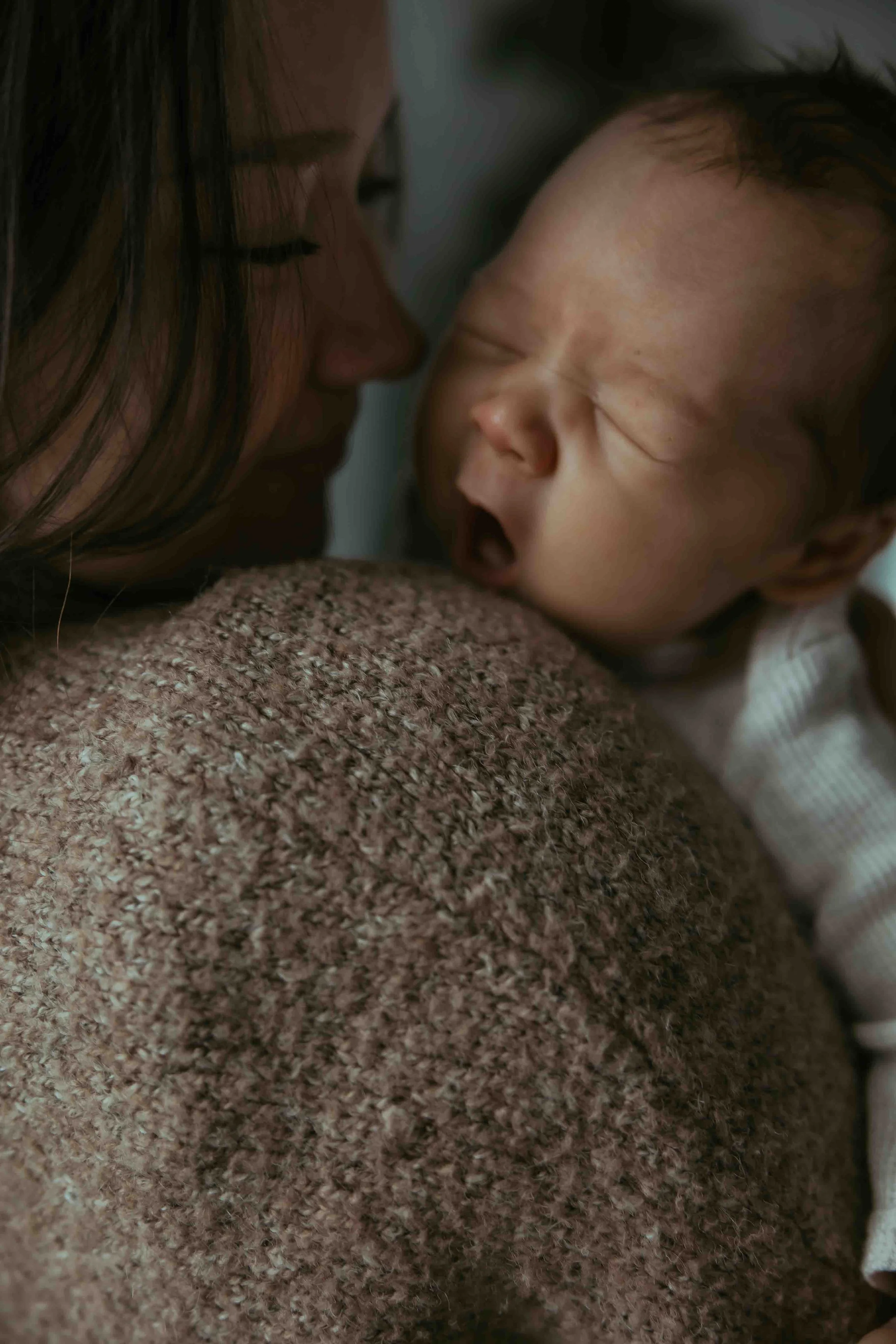 A yawning newborn with mother during newborn photography session 