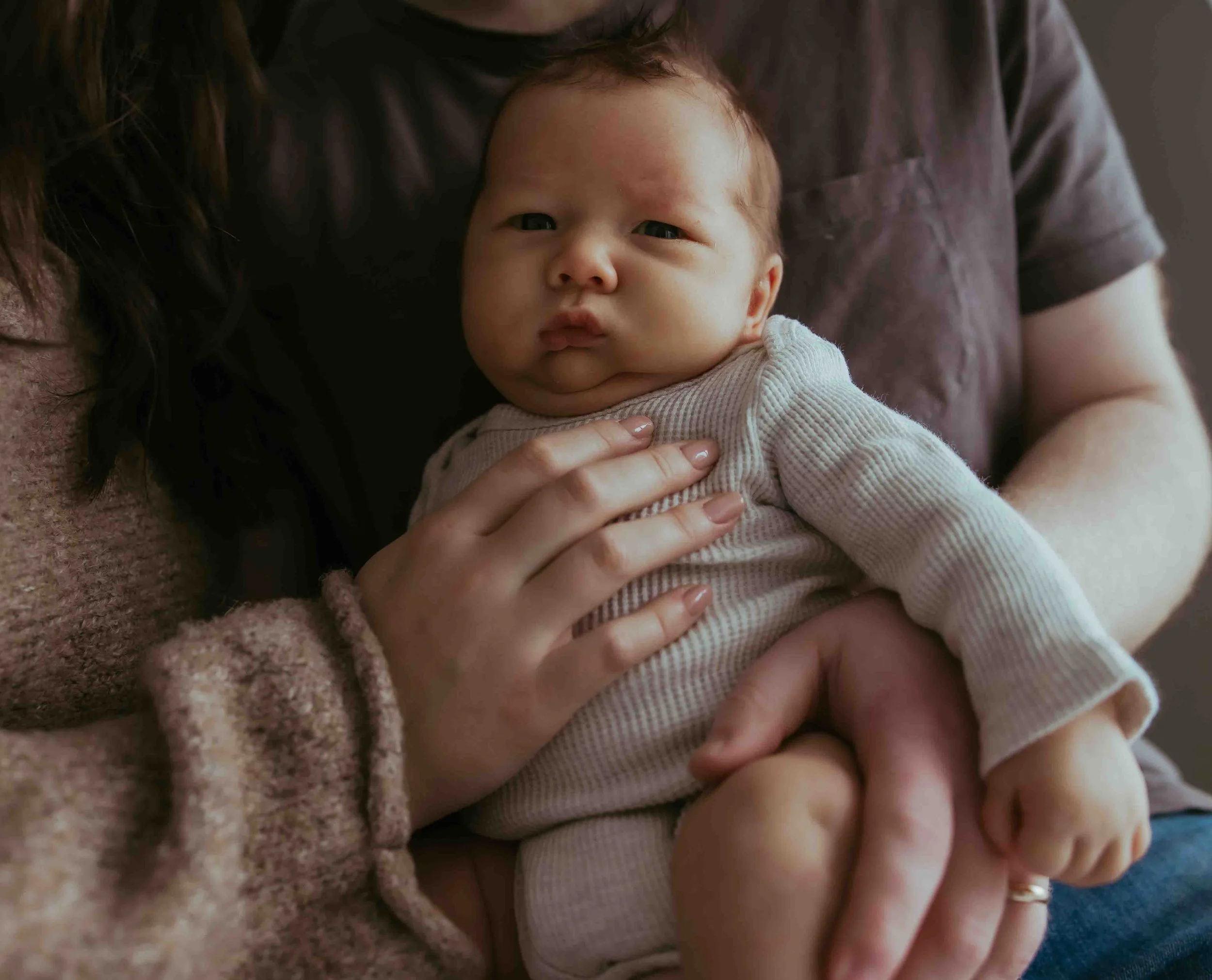 Newborn sitting with parents looking at camera 