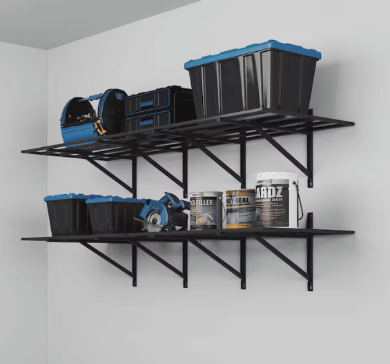 Black metal shelves mounted on a white wall holding various tools and storage bins in a garage or workshop.