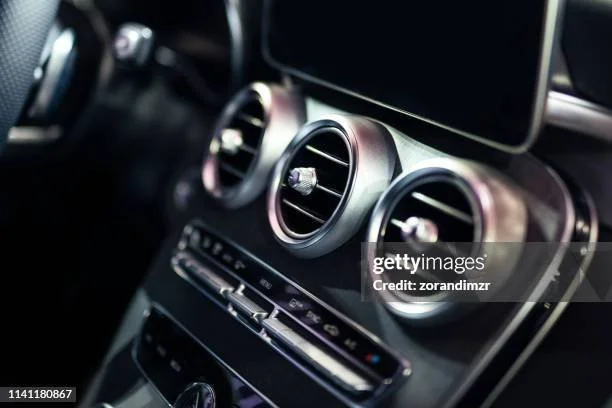 Close-up of three circular air vents on a car dashboard with a digital display above.