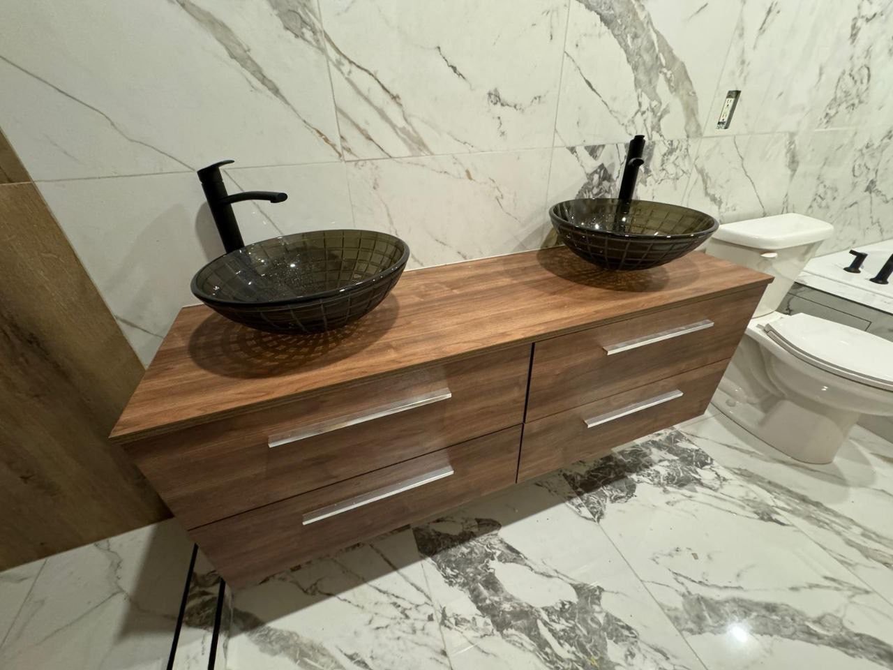 Modern floating vanity installation with double glass vessel sinks and matte black faucets
