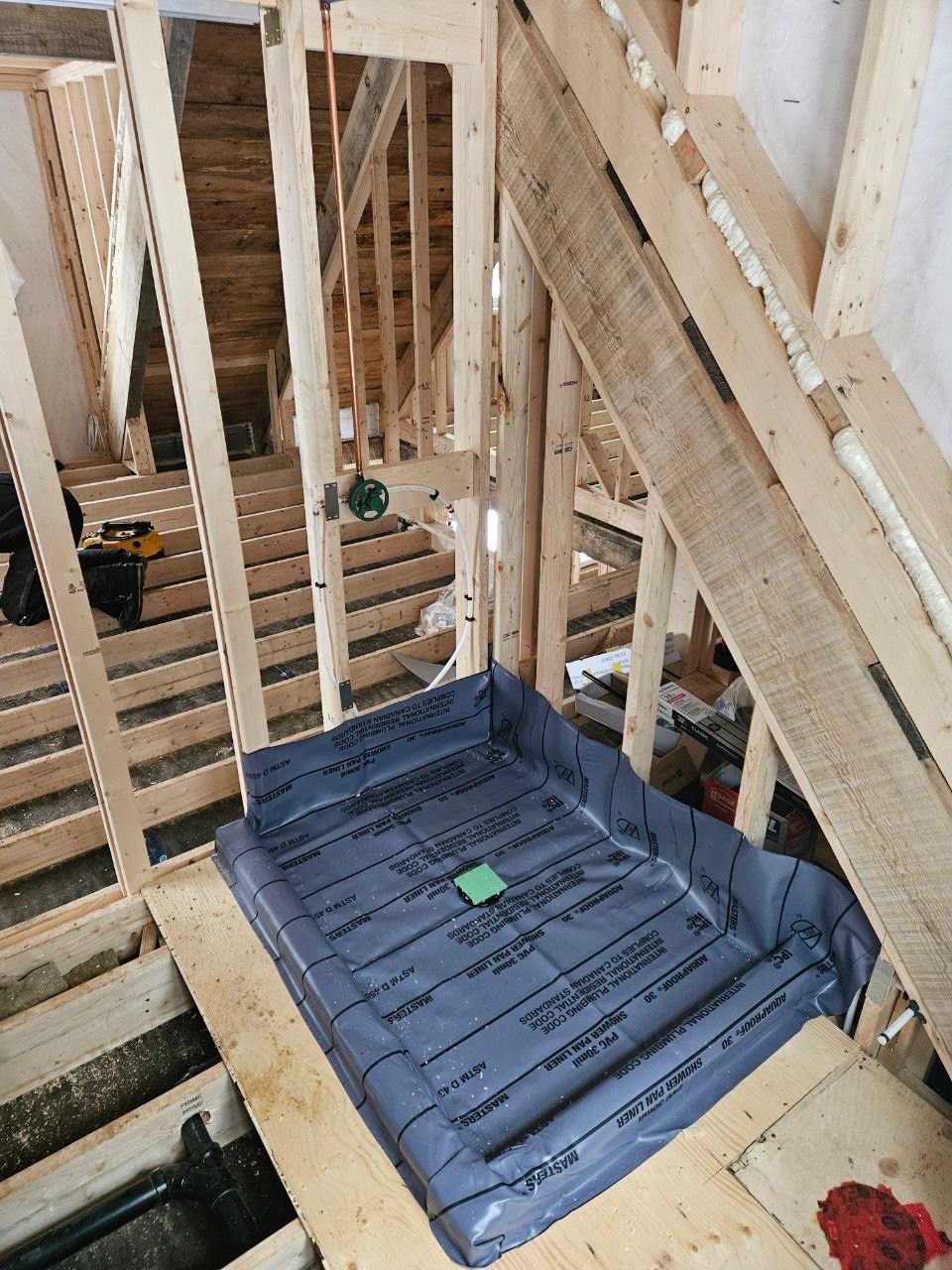Shower pan liner installation during bathroom renovation framing stage.