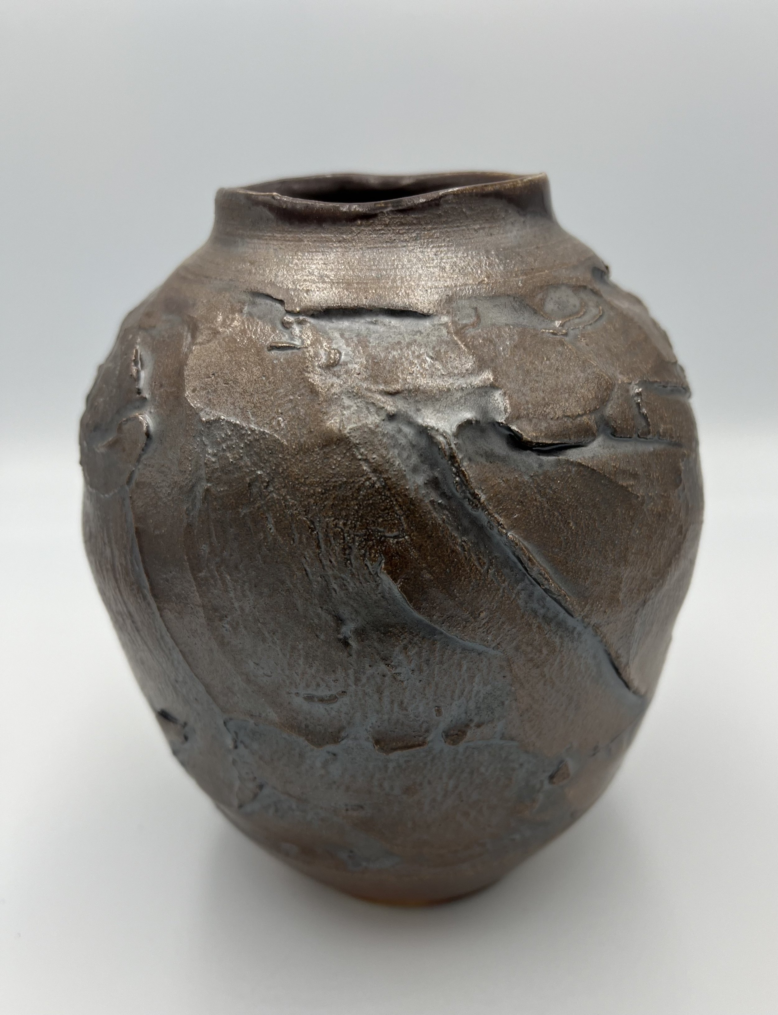 A textured, irregularly shaped ceramic vase with a rough surface and a dark brown glaze.
