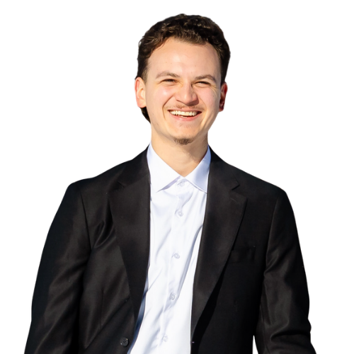 A smiling, local man in a black suit jacket and white shirt against a black background.