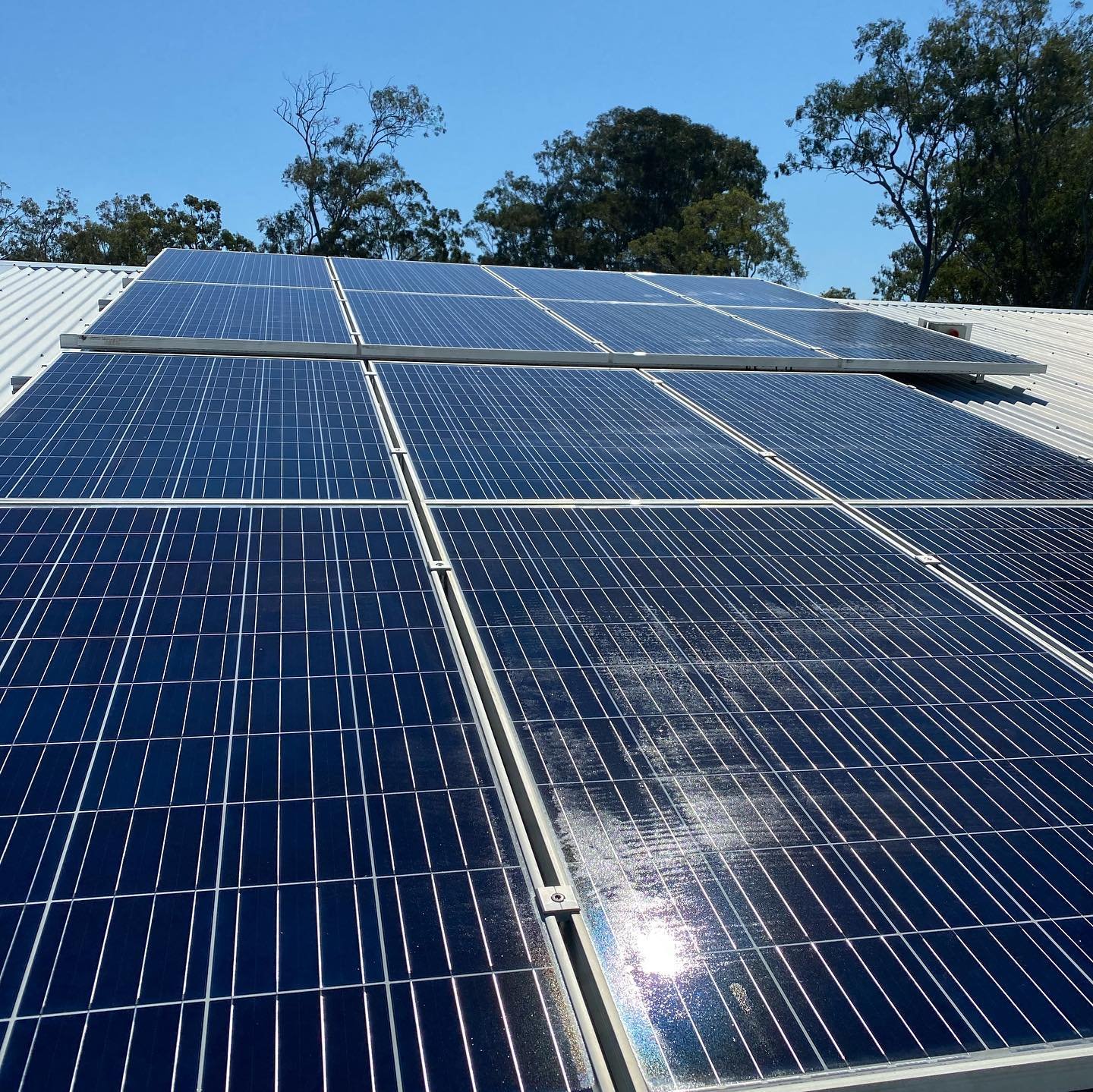 Solar panels on a roof with trees in the background.