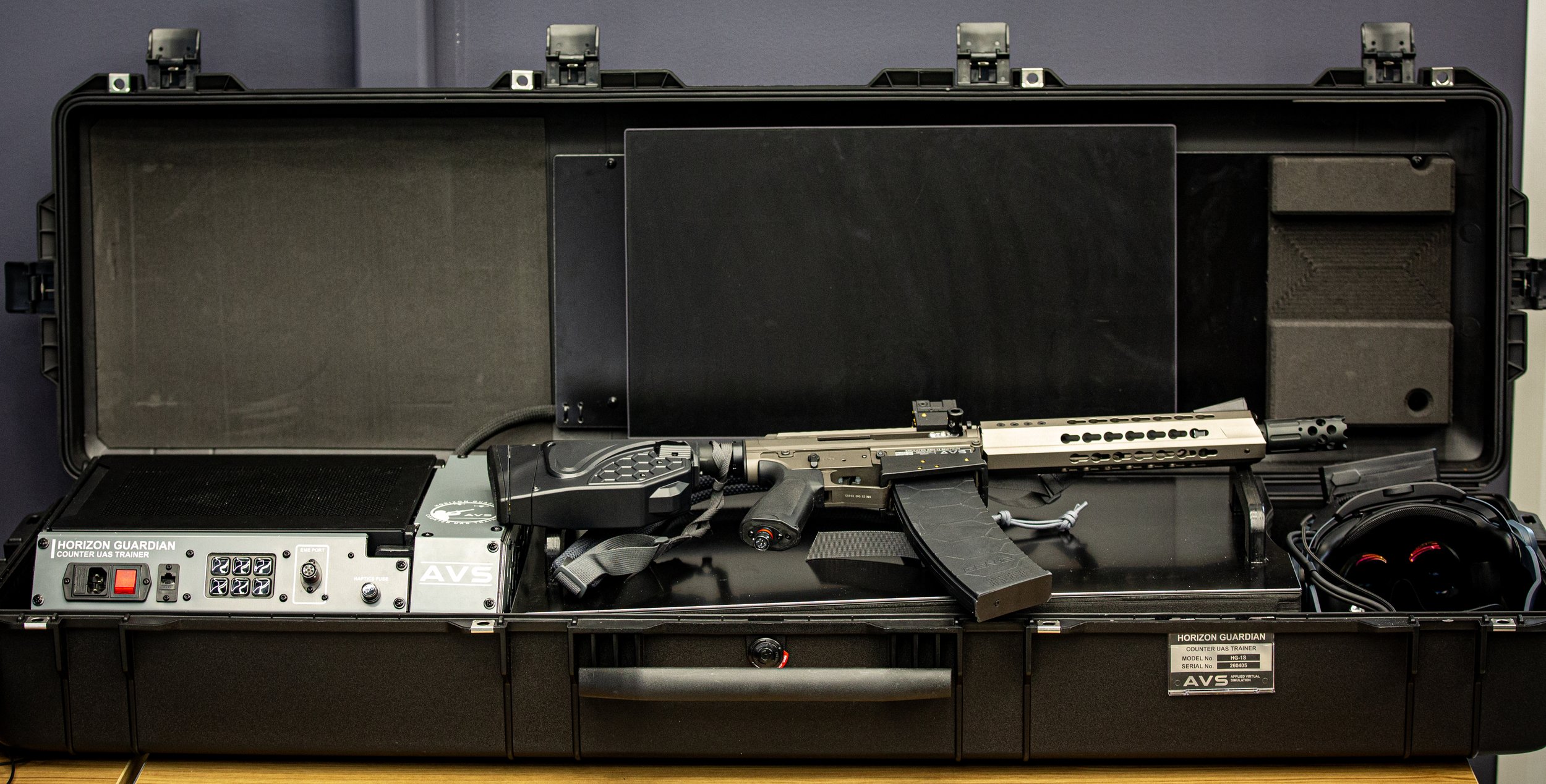 A black hard case containing a firearm, various electronic equipment, and accessories with foam padding, labeled Horizon Guardian Counter UAS Trainer.