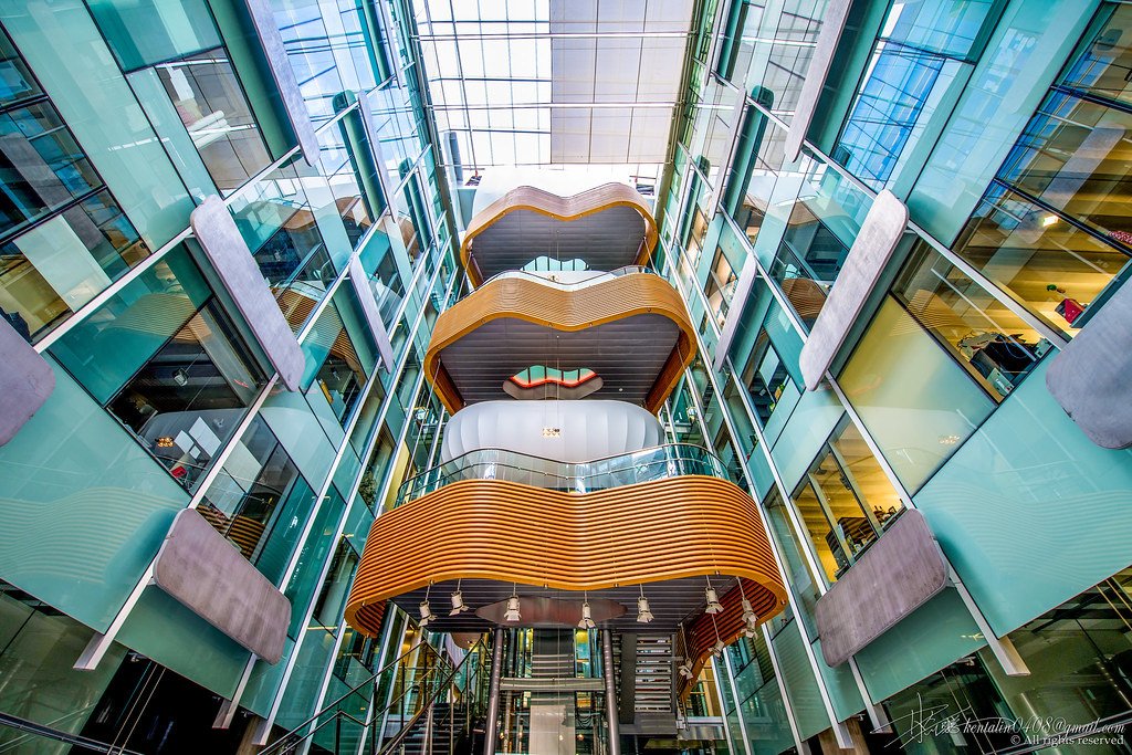 Interior view of a modern building with glass walls and colorful curved balconies.
