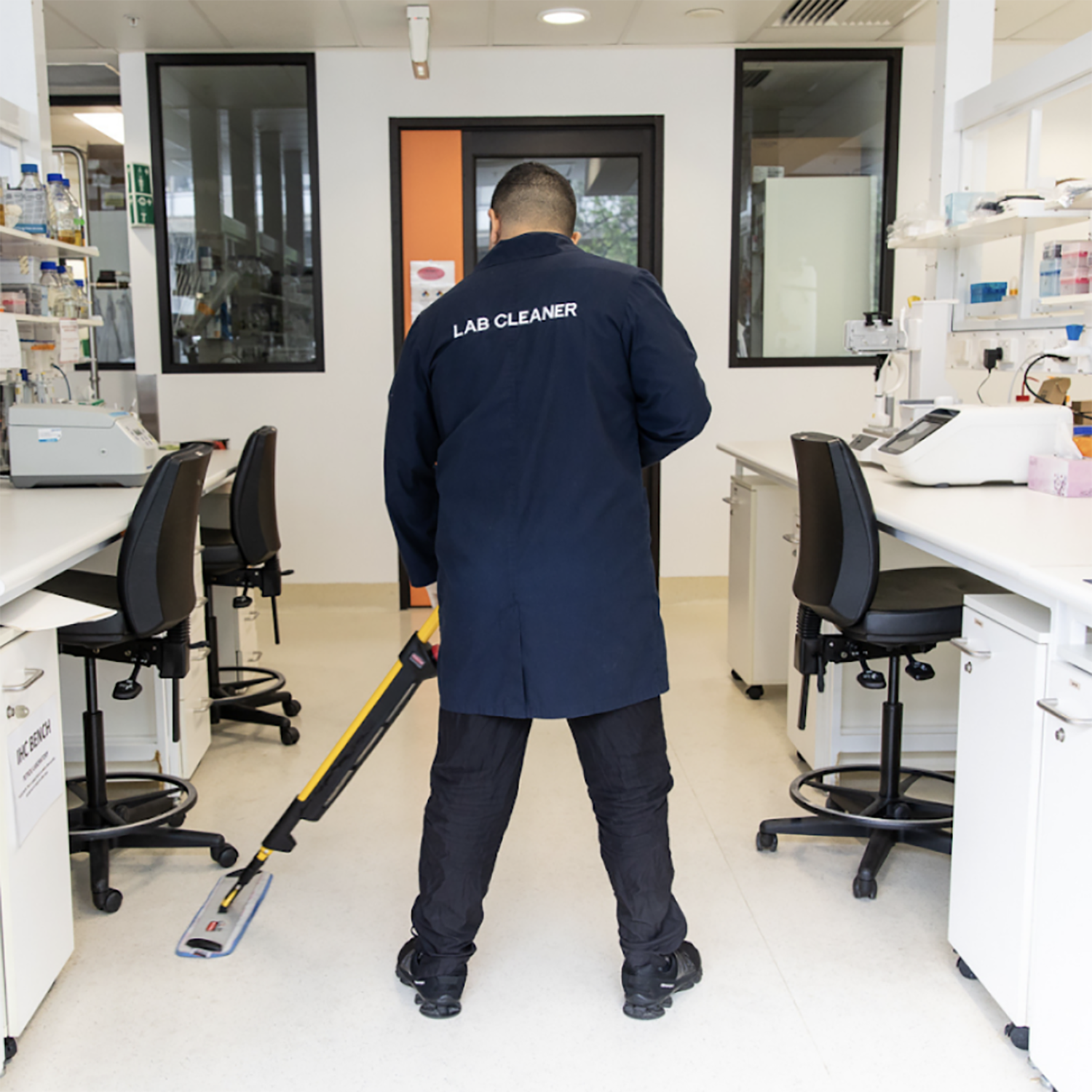 A person wearing a lab cleaner uniform mopping the floor in a laboratory.