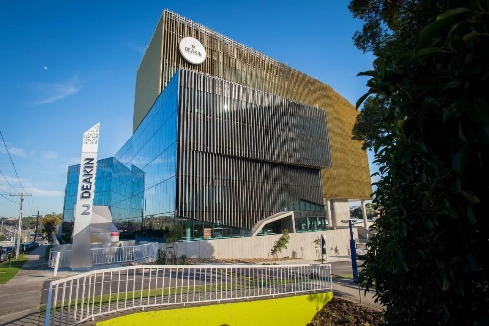 Modern commercial building with glass and metal design, displaying signs for Deakin University.