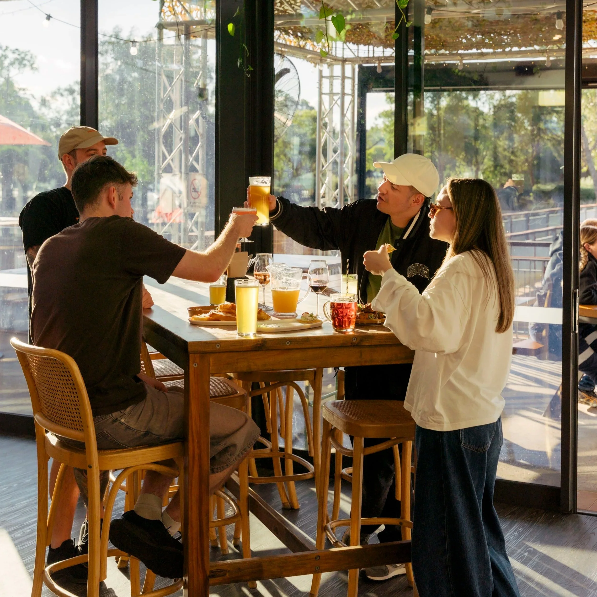 Plate of pizza, hummus with pita, salad, and drinks on a wooden table with people eating.