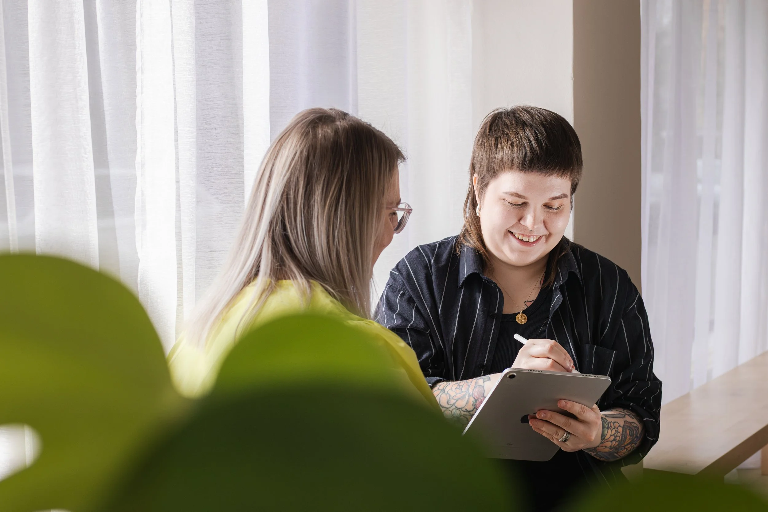 Riikkis Graphic työskentelemässä yhdessä asiakkaansa kanssa graafisen suunnittelun äärellä