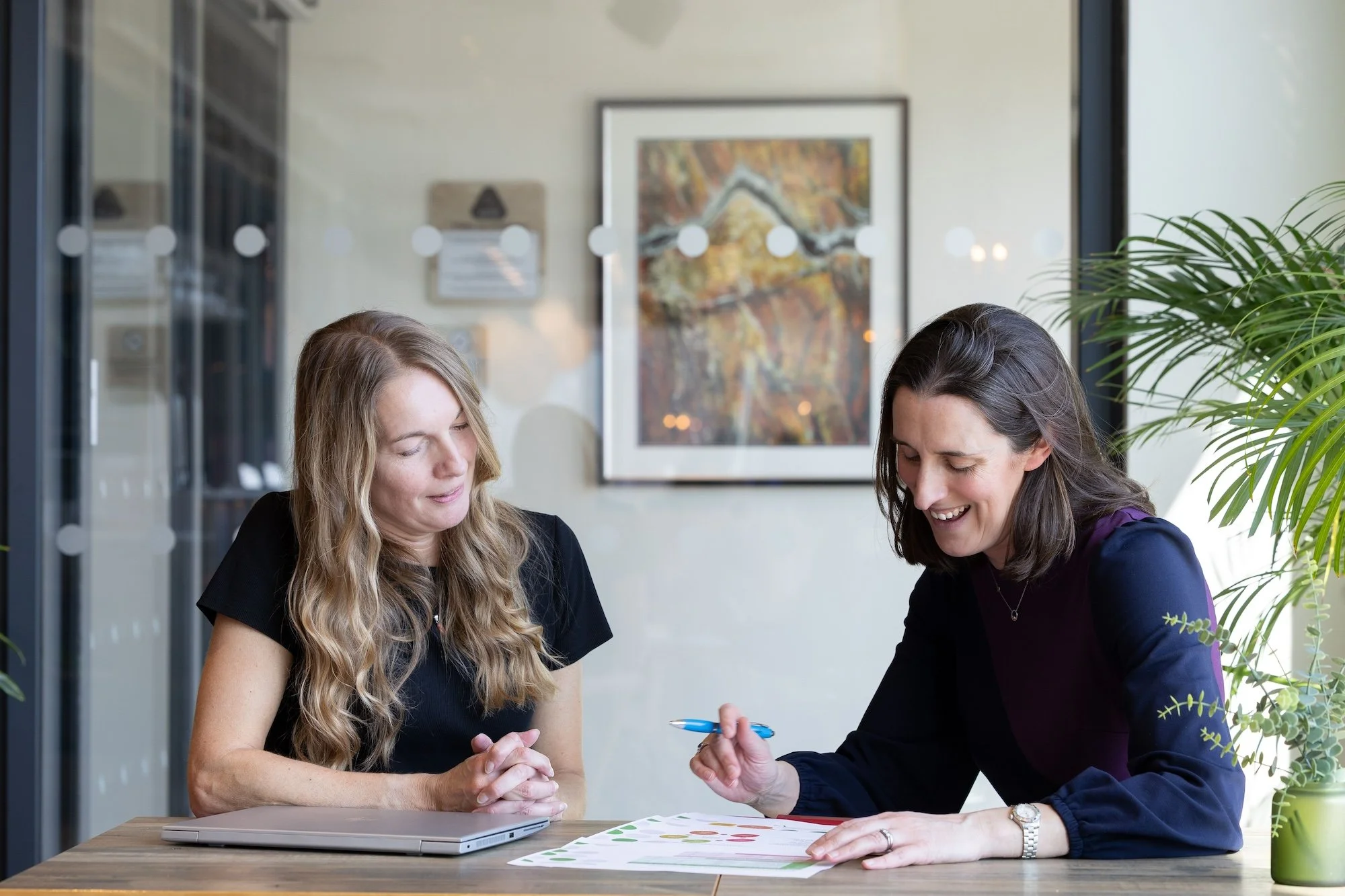 Kathy Seymour and Katy Willis talking and reviewing documents at a table in an office setting.