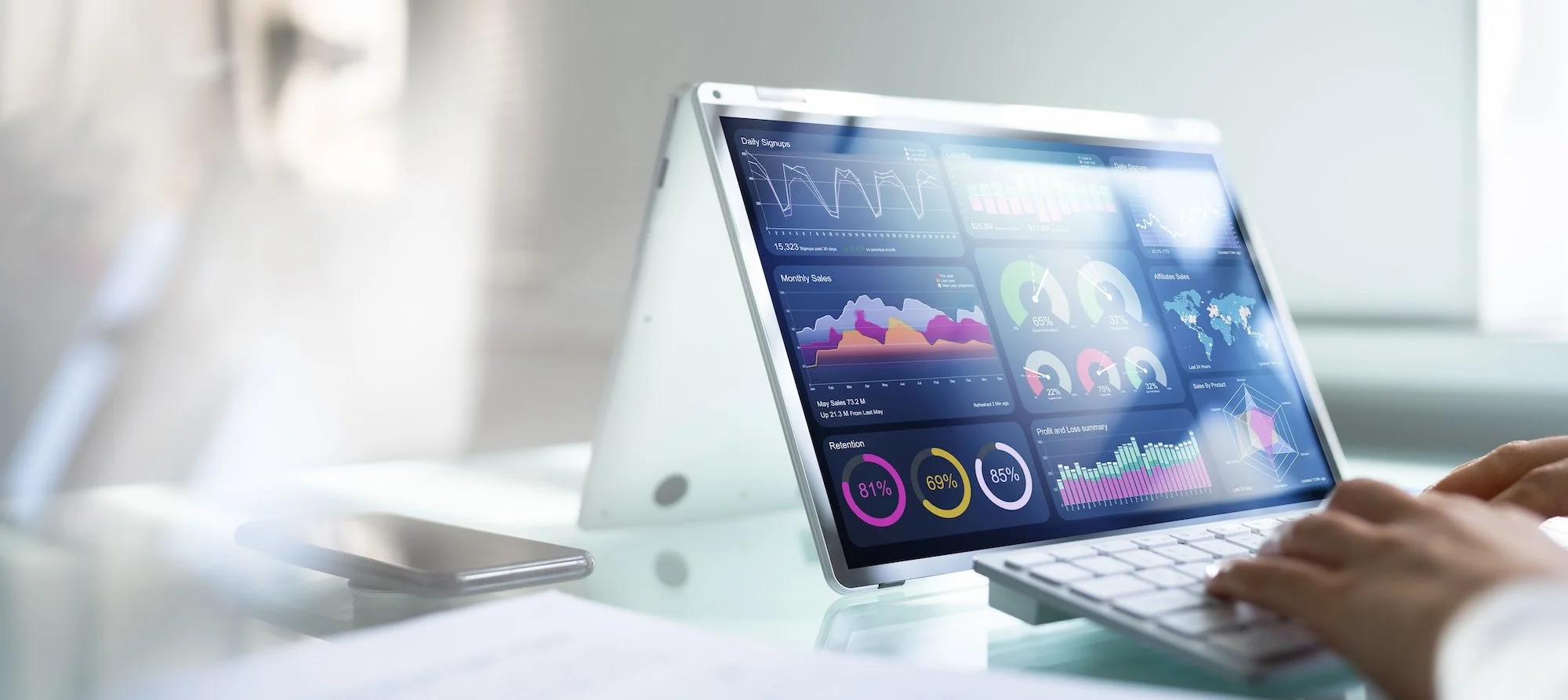 Person using a tablet displaying data analytics charts on a desk.