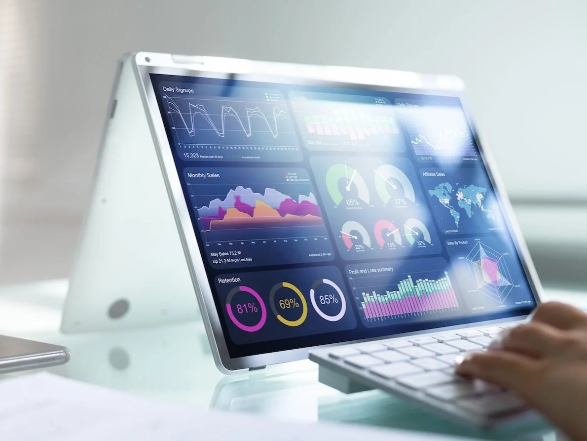 Person using a tablet displaying data analytics charts on a desk.