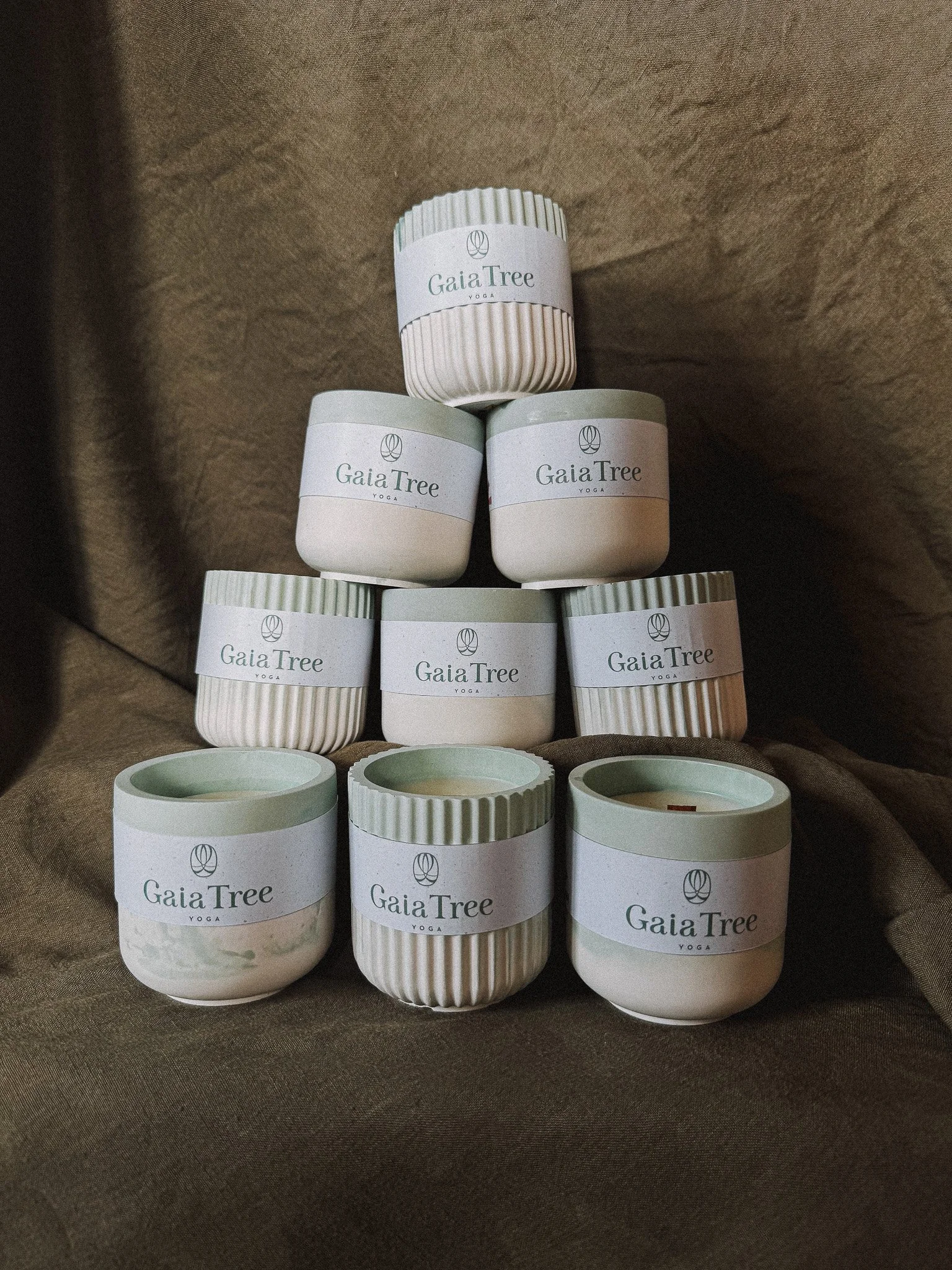 Un empilement de bougies parfumées de la marque Treize Bougies, personnalisées par le client : Gaia Tree, toutes portant une étiquette blanche avec le logo et le nom de la marque.