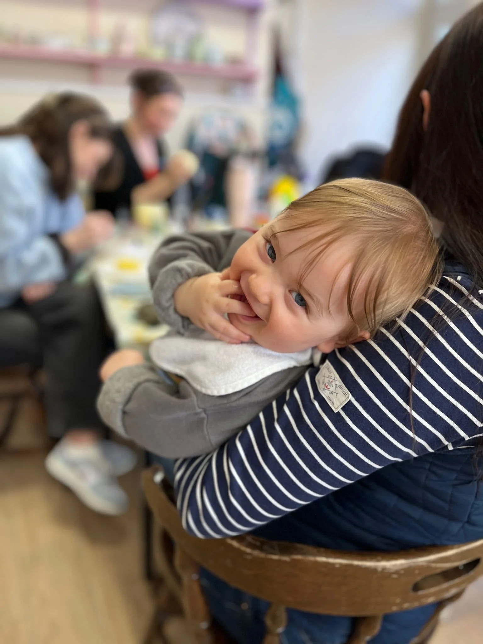 baby being held by mother whilst others paint pots.jpeg