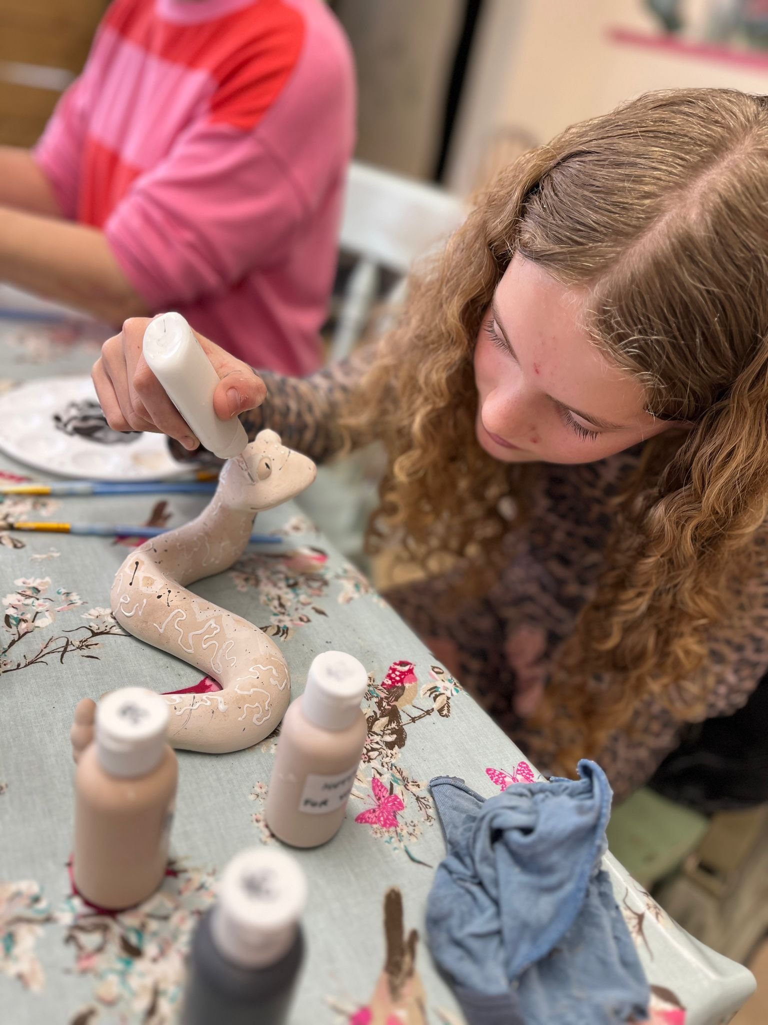 girl painting a pottery snake.jpeg