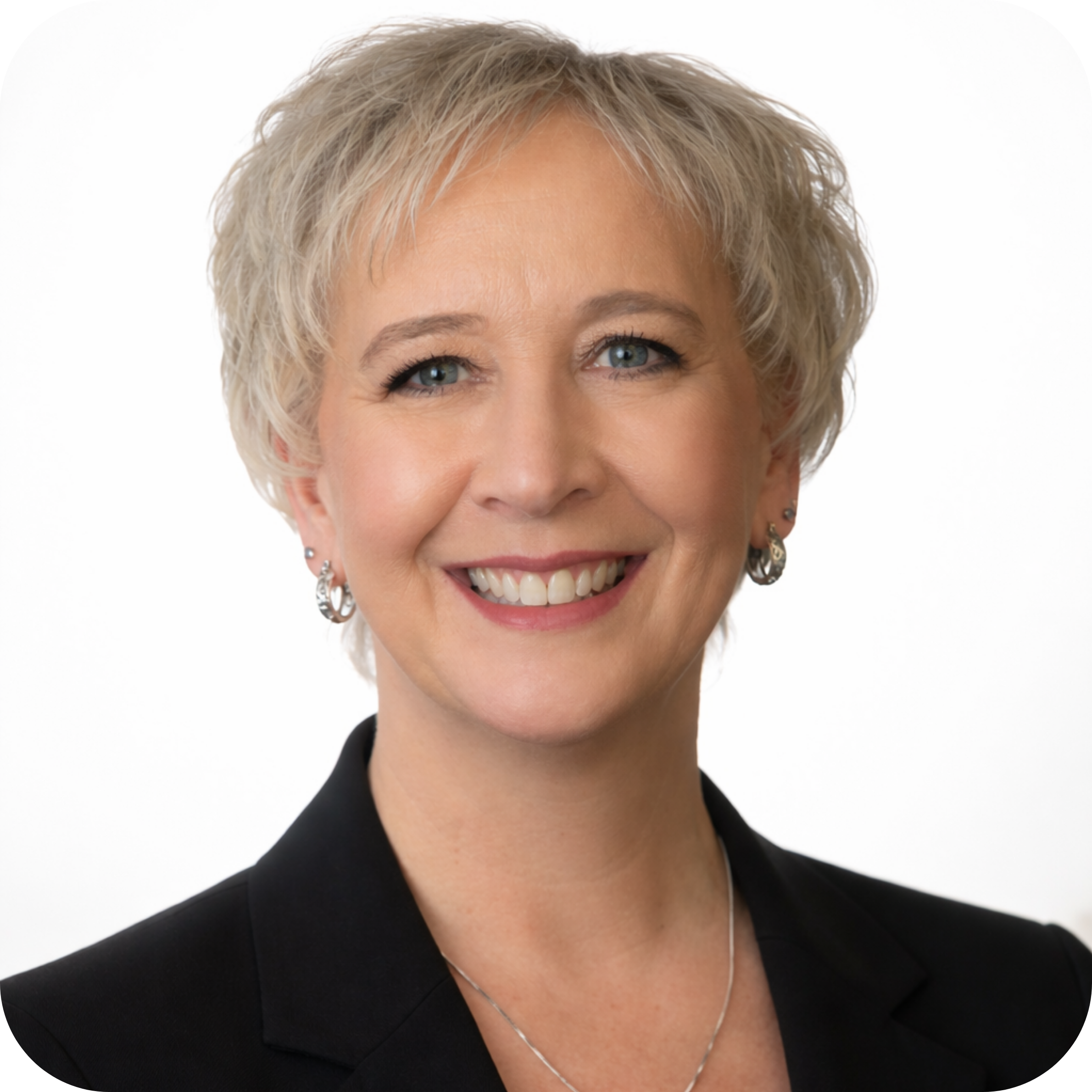 A woman with short blonde hair smiling, in an indoor setting with blurred background including a bicycle.