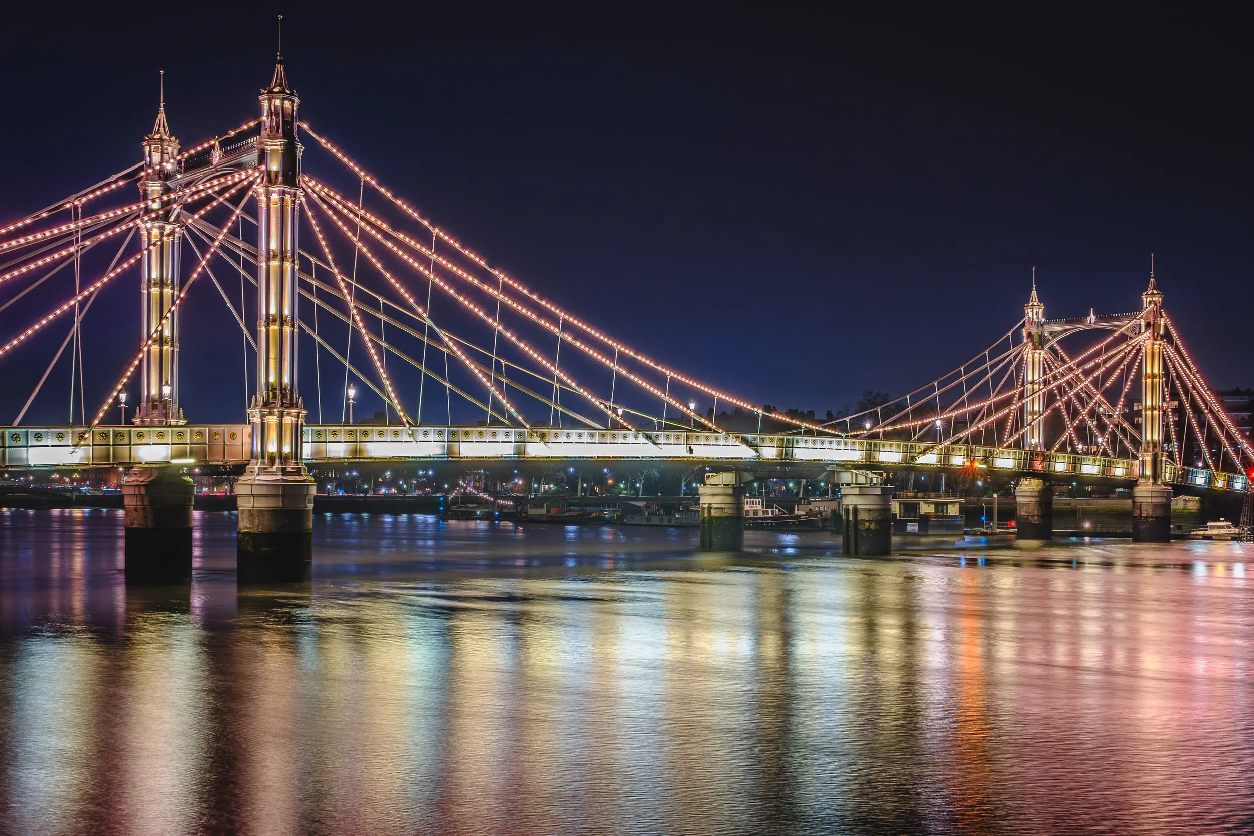 Albert Bridge in London illuminated at night over the River Thames.