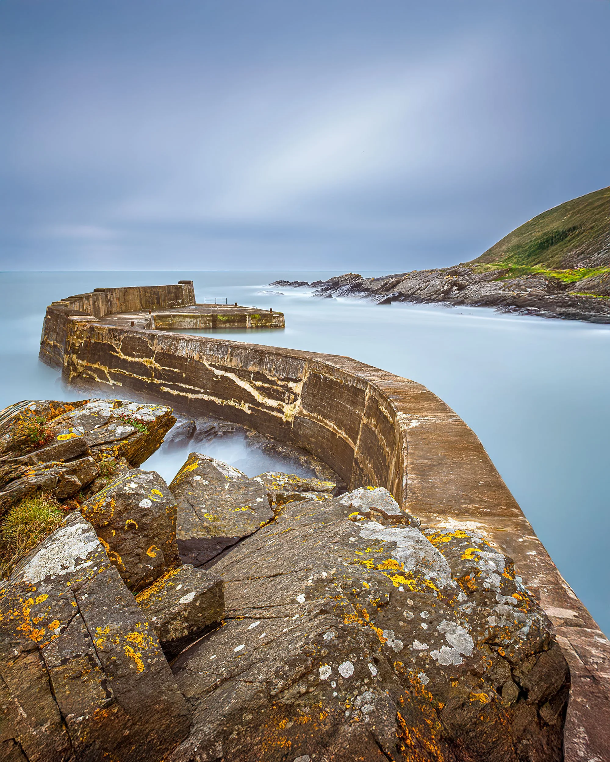 A long seascape image of Collieston harbour wall in Aberdeenshire Scotland.