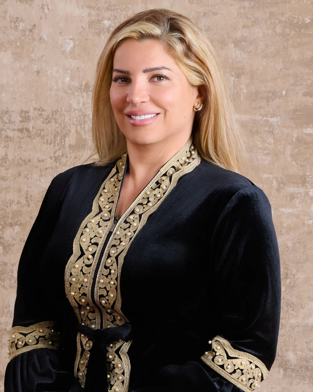 Dr. Rama Hijjawi, mental health and family relationships consultant, smiling in a black and gold embroidered jacket