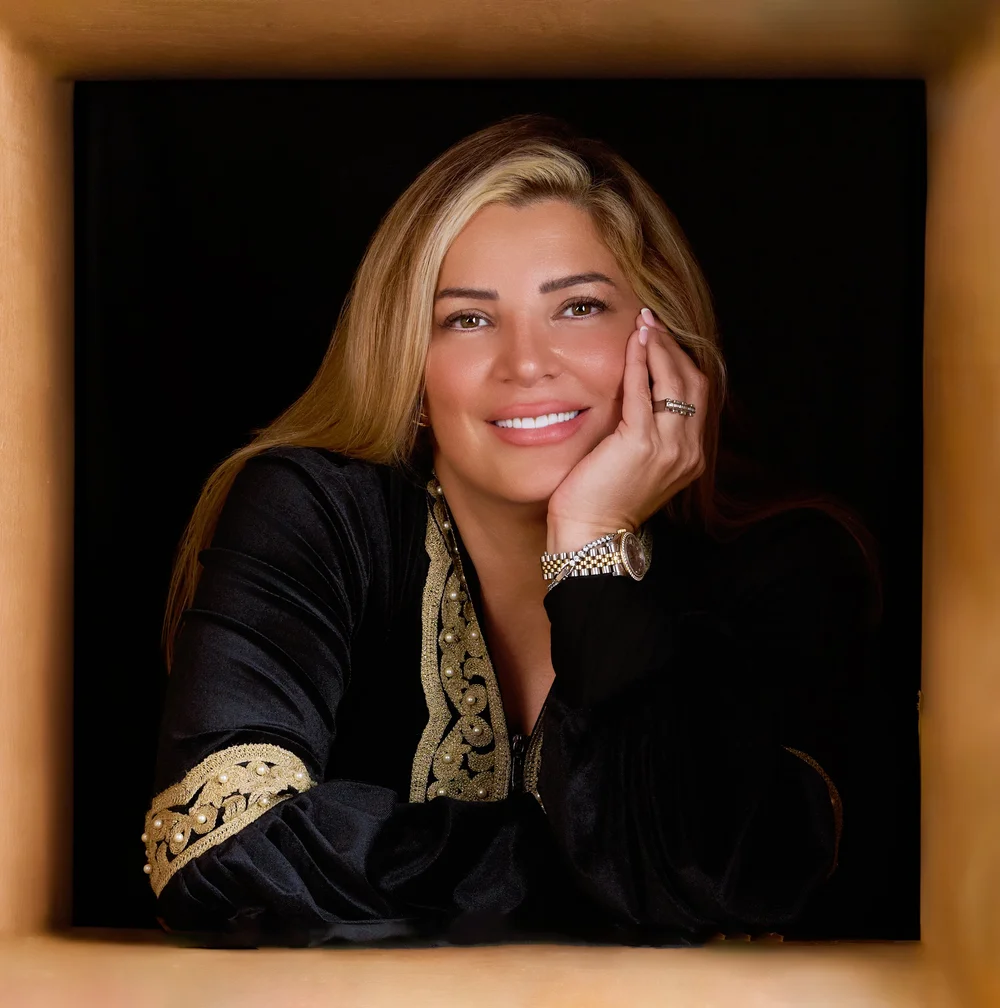 Dr. Rama Hijjawi resting her chin on her hand, framed in warm wood