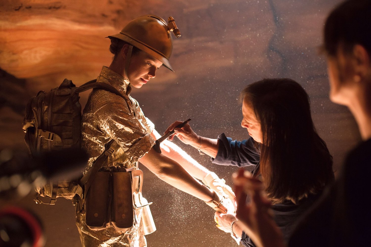 Actor in a gold uniform and helmet receiving a tattoo on the set of The Seven Worlds
