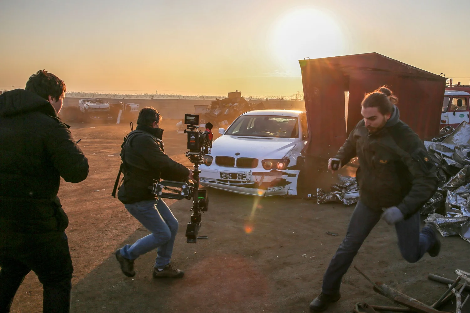 Crew filming a car crash scene at sunset for the Kontrafakt music video