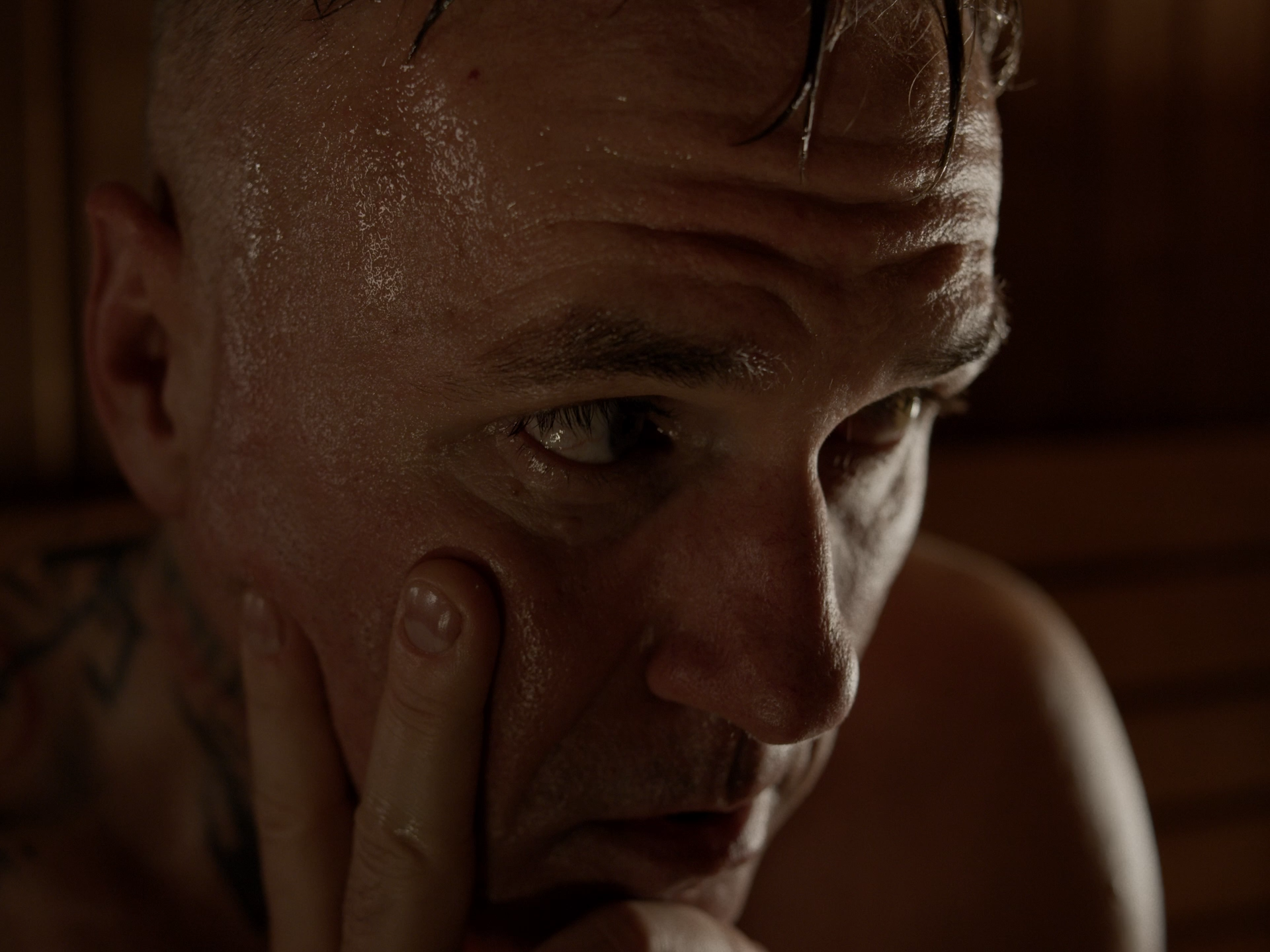 Nahaufnahme eines Mannes mit nasser Haut, der nachdenklich mit Finger an der Wange berührt