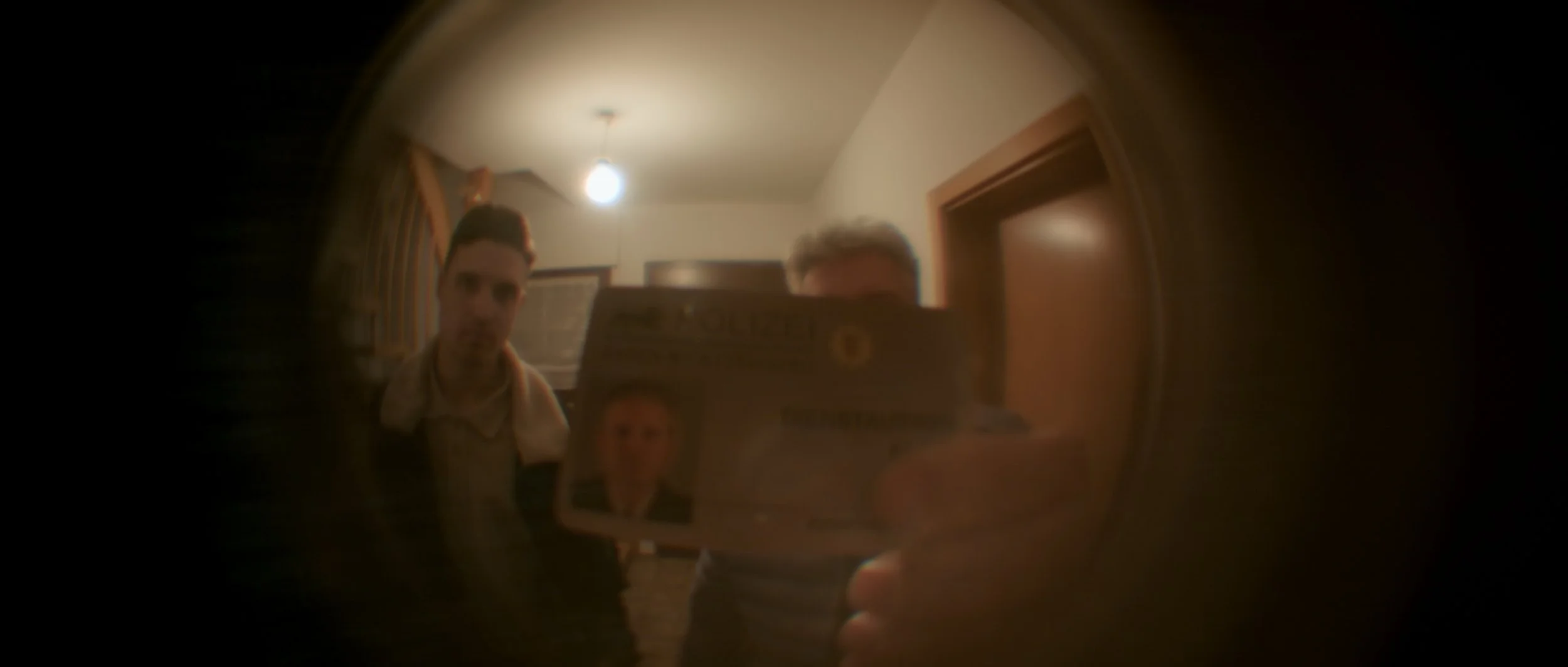 Zwei Männer schauen durch einen Türspion, wobei eine Person einen Ausweis hält.