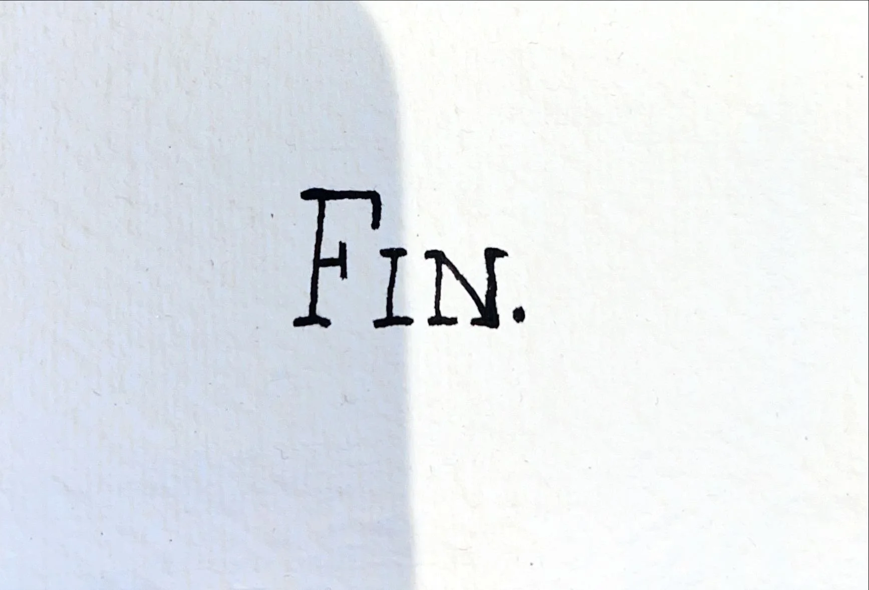 A white paper with the word 'FIN.' handwritten in black ink.