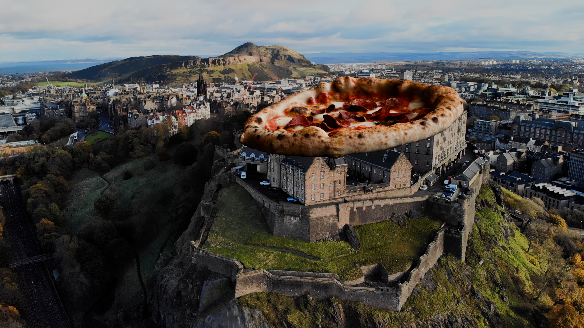 A cityscape with a large pepperoni pizza floating above a castle on a hill, with mountains and a cloudy sky in the background.