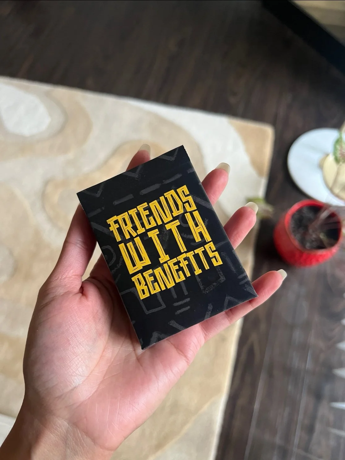A hand holding a black pack labeled "Friends with Benefits" in bold yellow text.