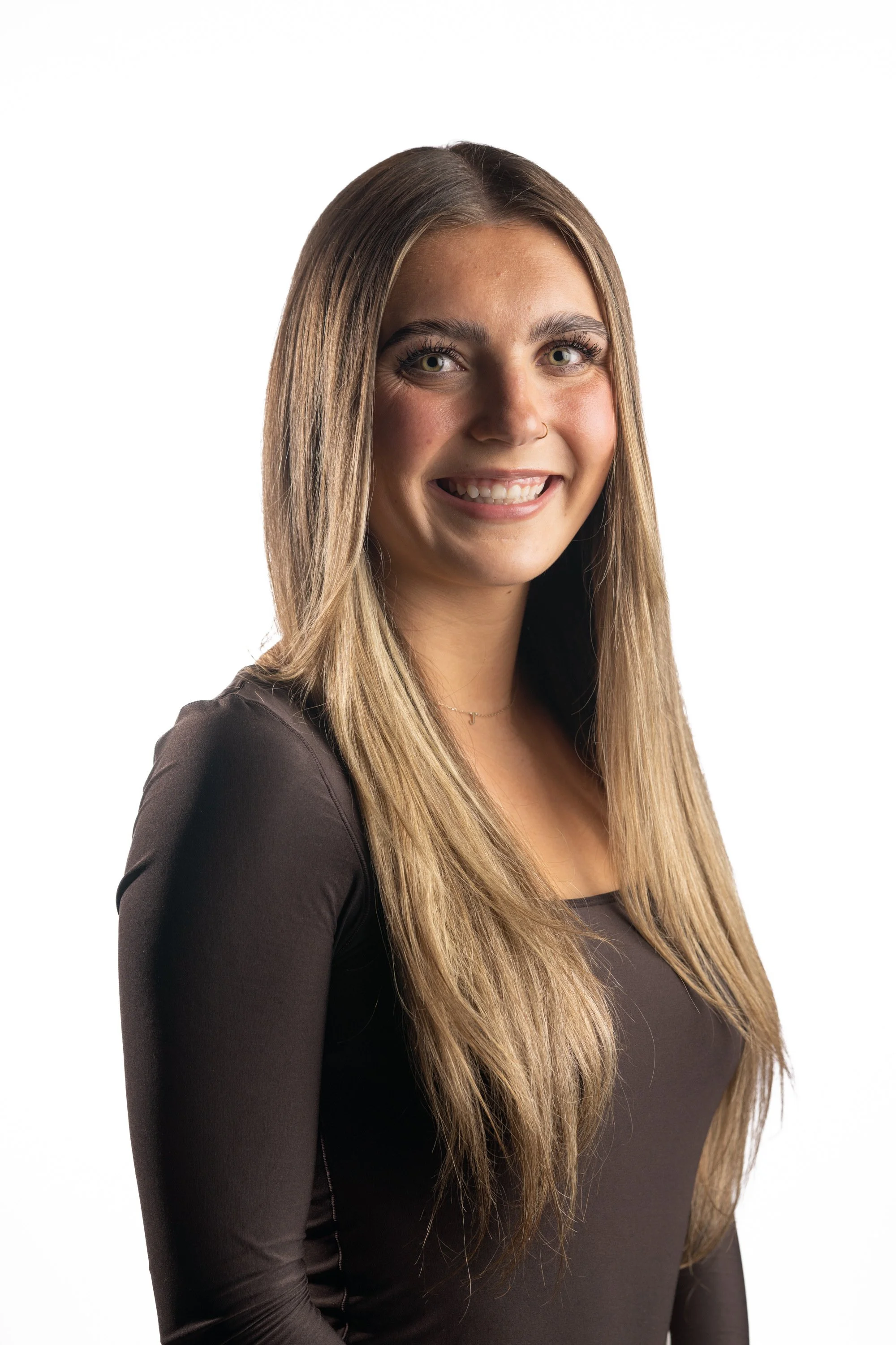 Portrait of a young woman with long, light brown hair, smiling and wearing a black top, against a white background.