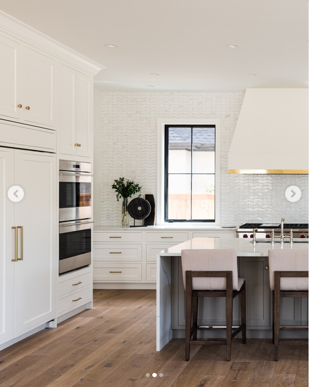 White kitchen with white tile backpslash, hood with gold accents