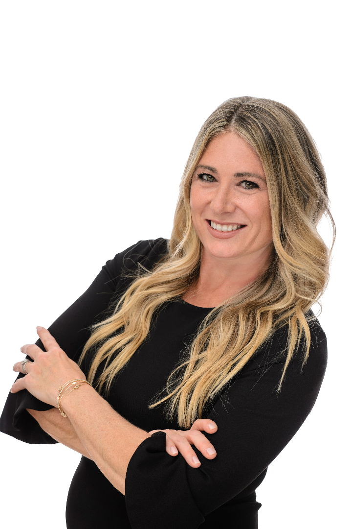 A smiling woman with long blonde hair, wearing a black top, crossing her arms, posing confidently.