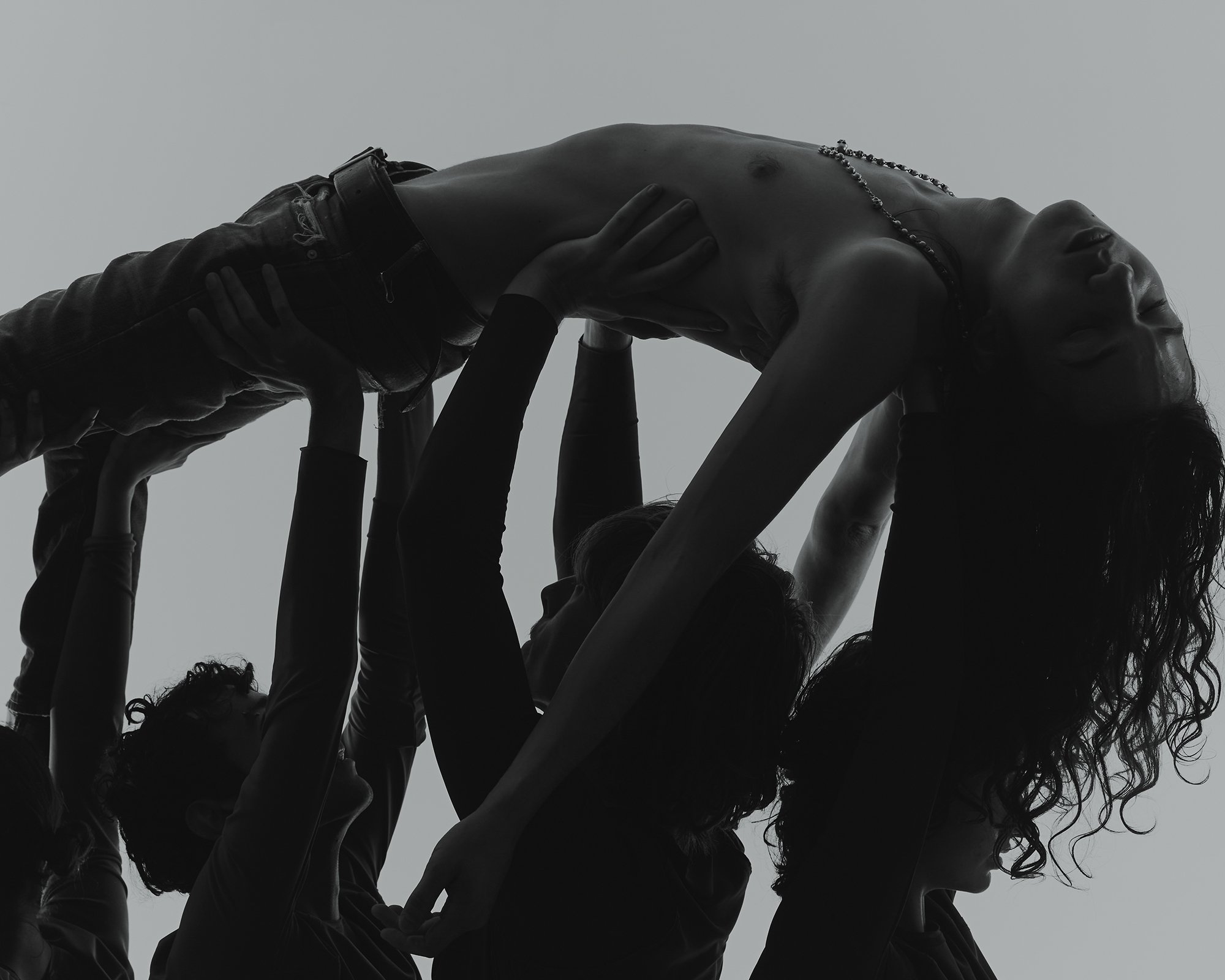 A group of people forming a human pyramid, with one woman at the top arching backwards.