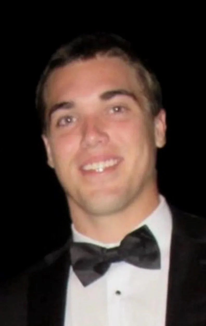 Person in white shirt smiling indoors with a "LOVE" sign in the background.