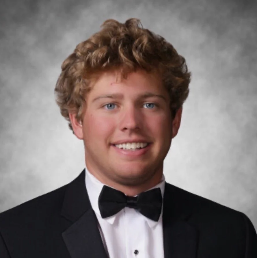 Young man in a tuxedo and bow tie smiling.