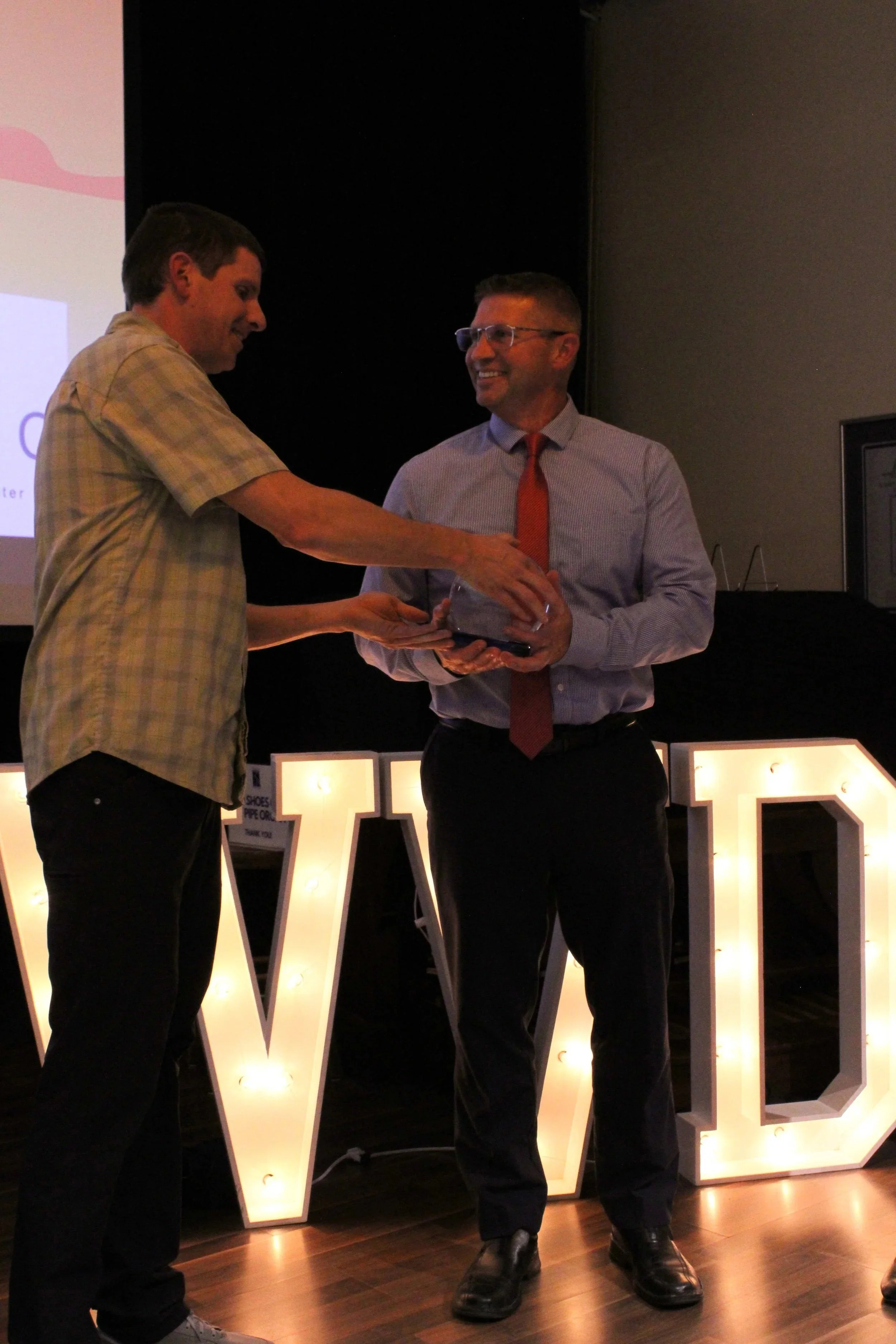 2025 Community Peacebuilder Lance Noell receiving award from 2024 Community Peacebuilder Bob Mark