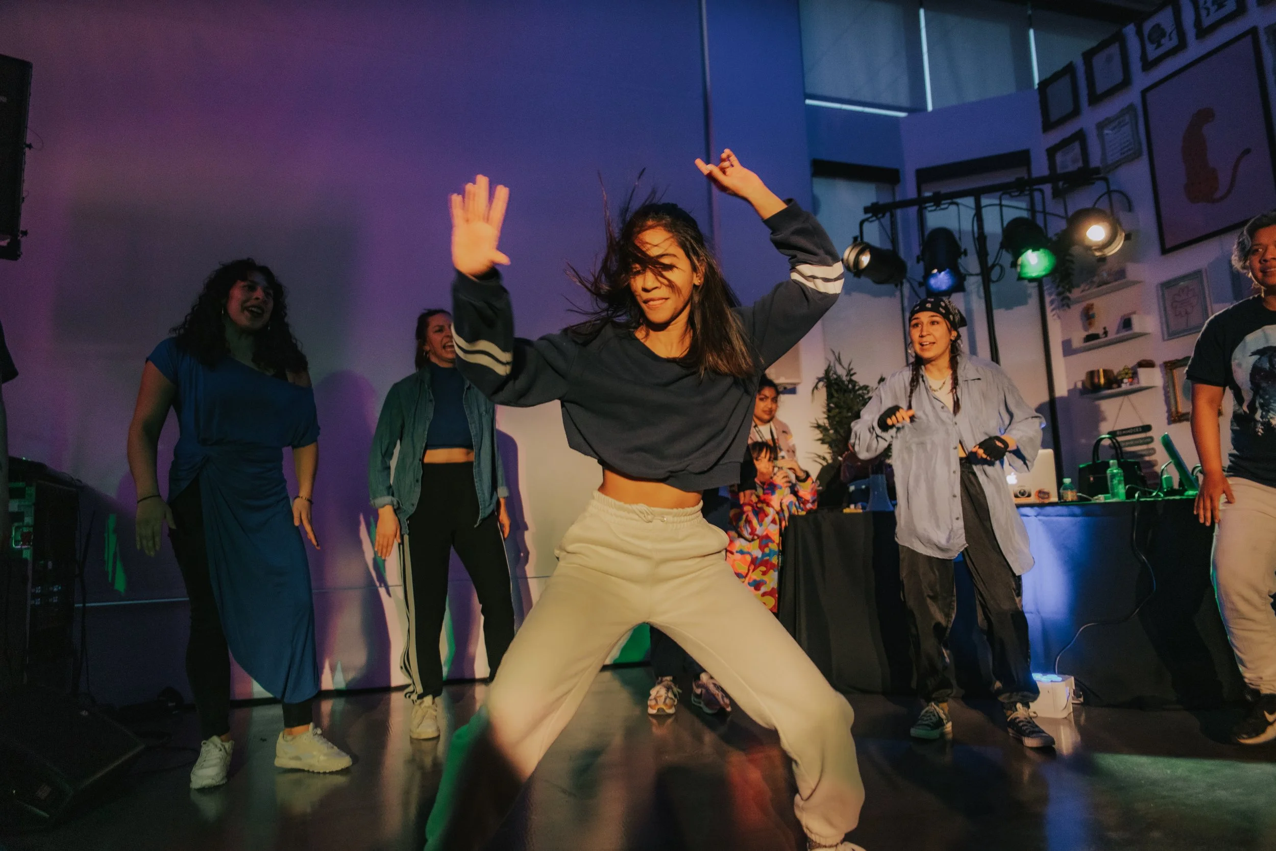 Group of young women dancing and enjoying a party in a colorful, lively atmosphere with stage lights and modern decor.