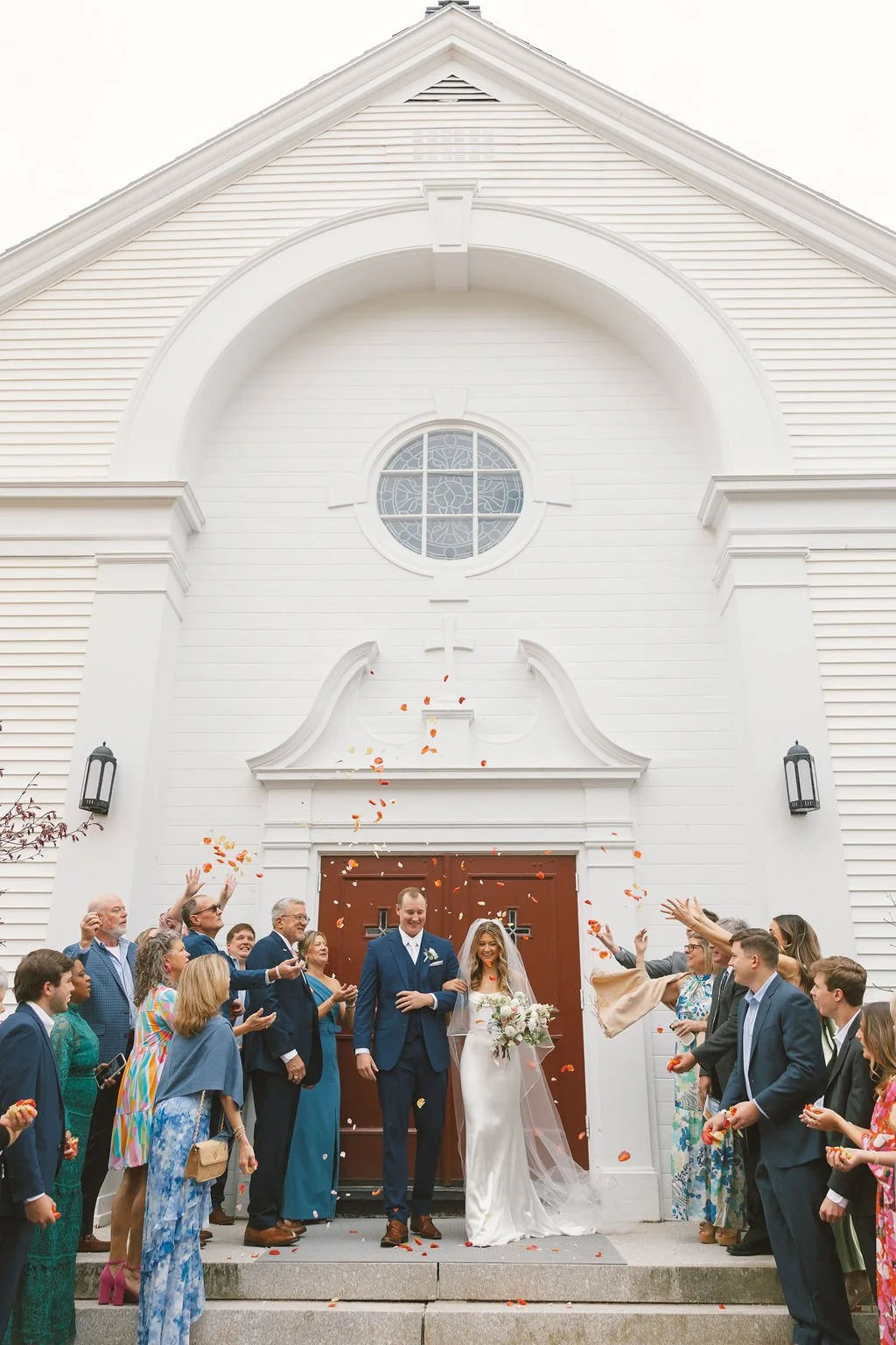 Wedding couple exiting church with guests throwing flower petals