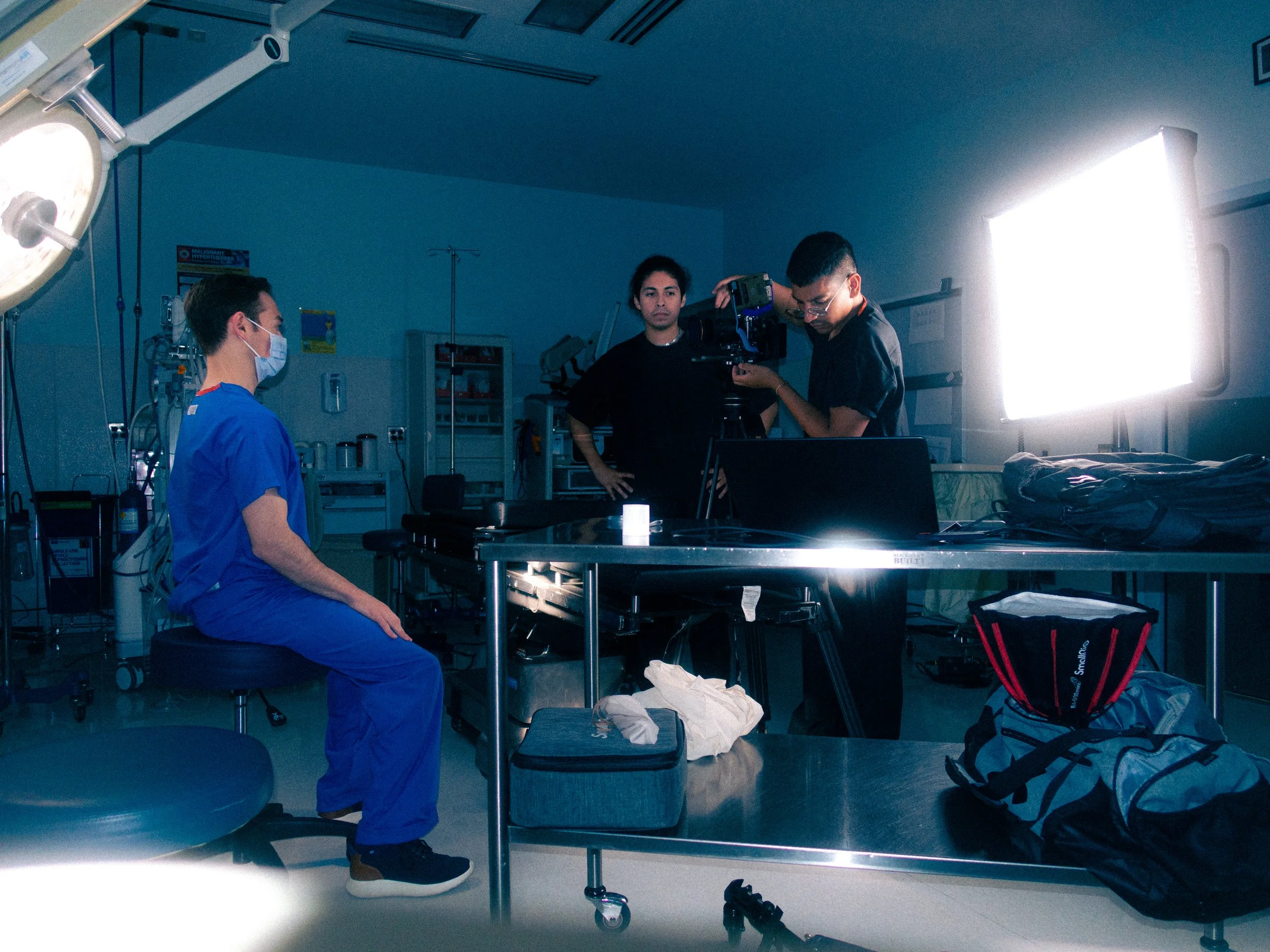 A group of people in an operating room preparing for surgery, with medical equipment and bright lighting.